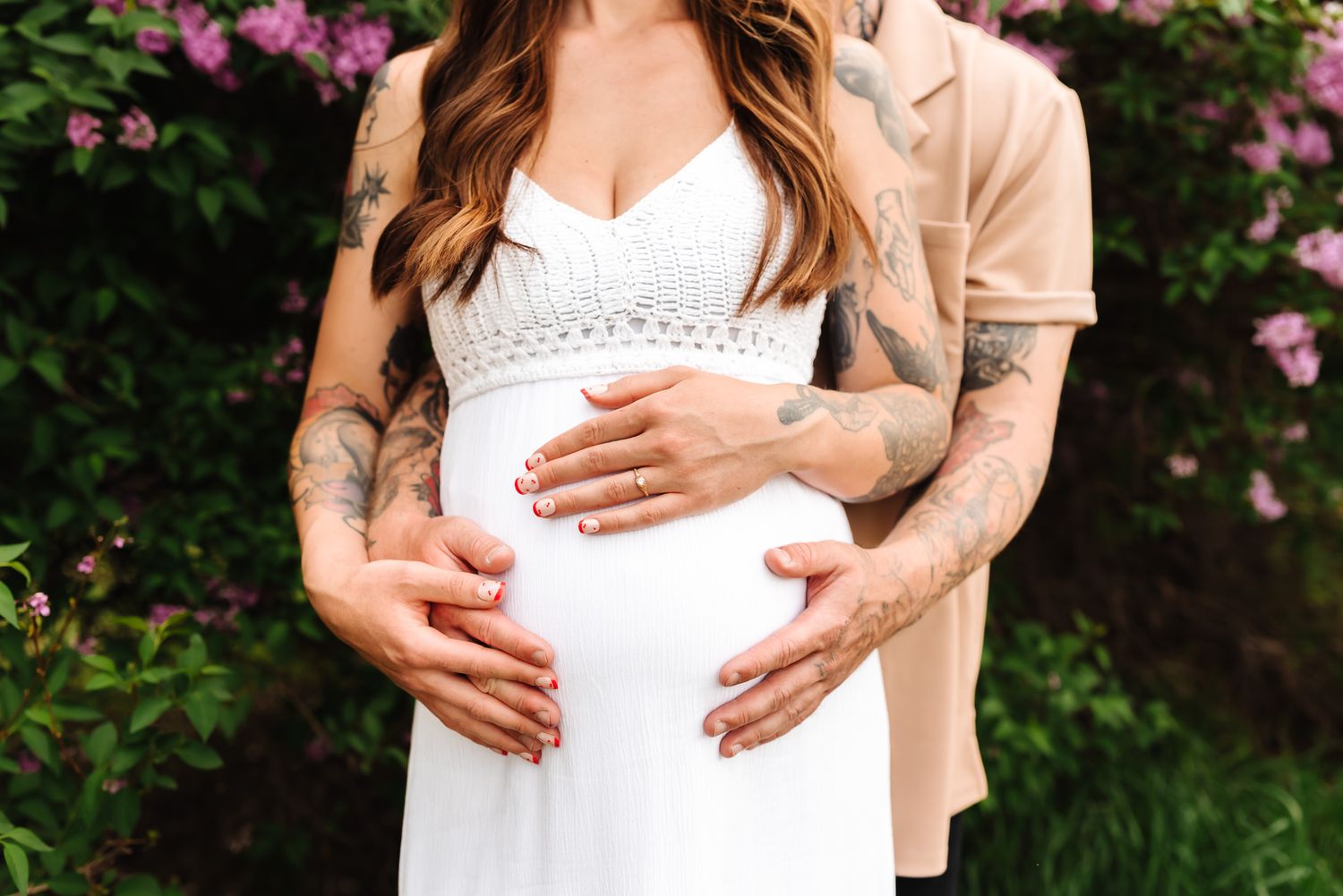 Intimate maternity moment captured against lush green foliage.