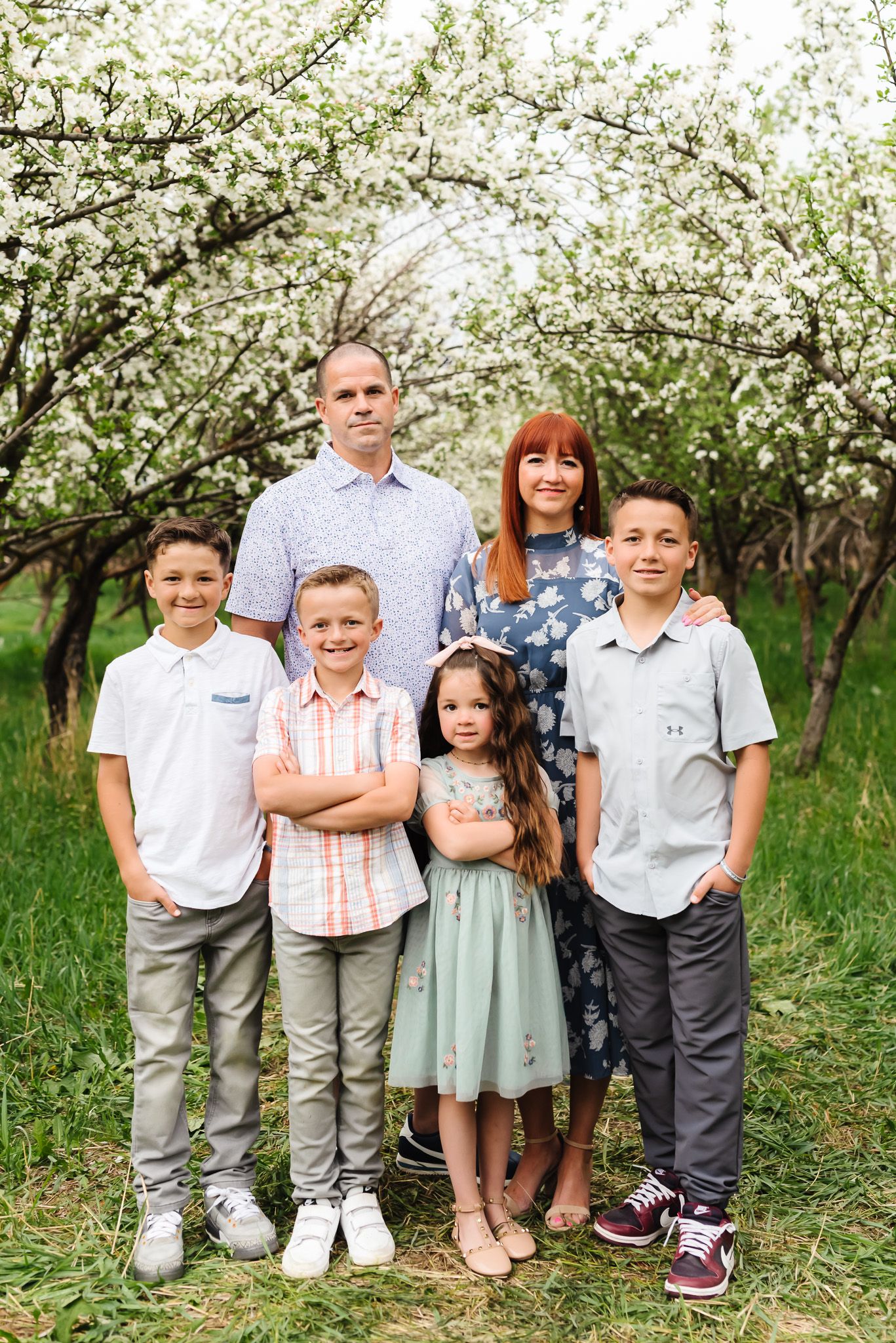 Group portrait of children standing together under flowering trees in springtime.