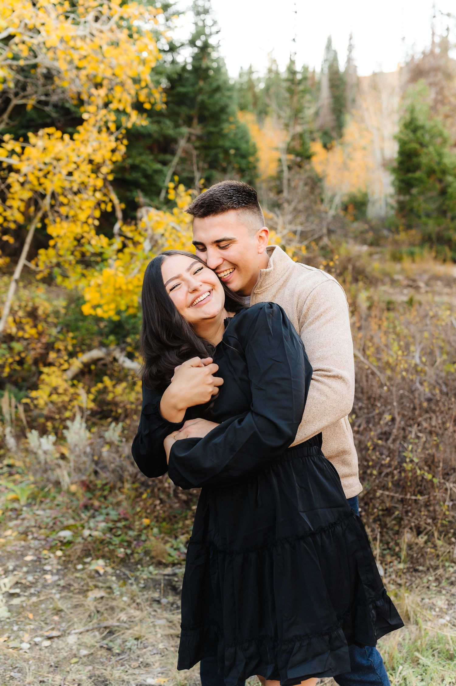A romantic embrace between a couple surrounded by fall foliage in the mountains.