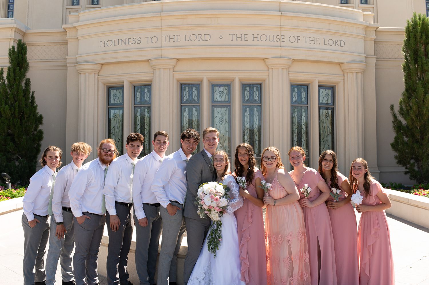 Wedding party members lined up outside a grand architectural building in formal attire.