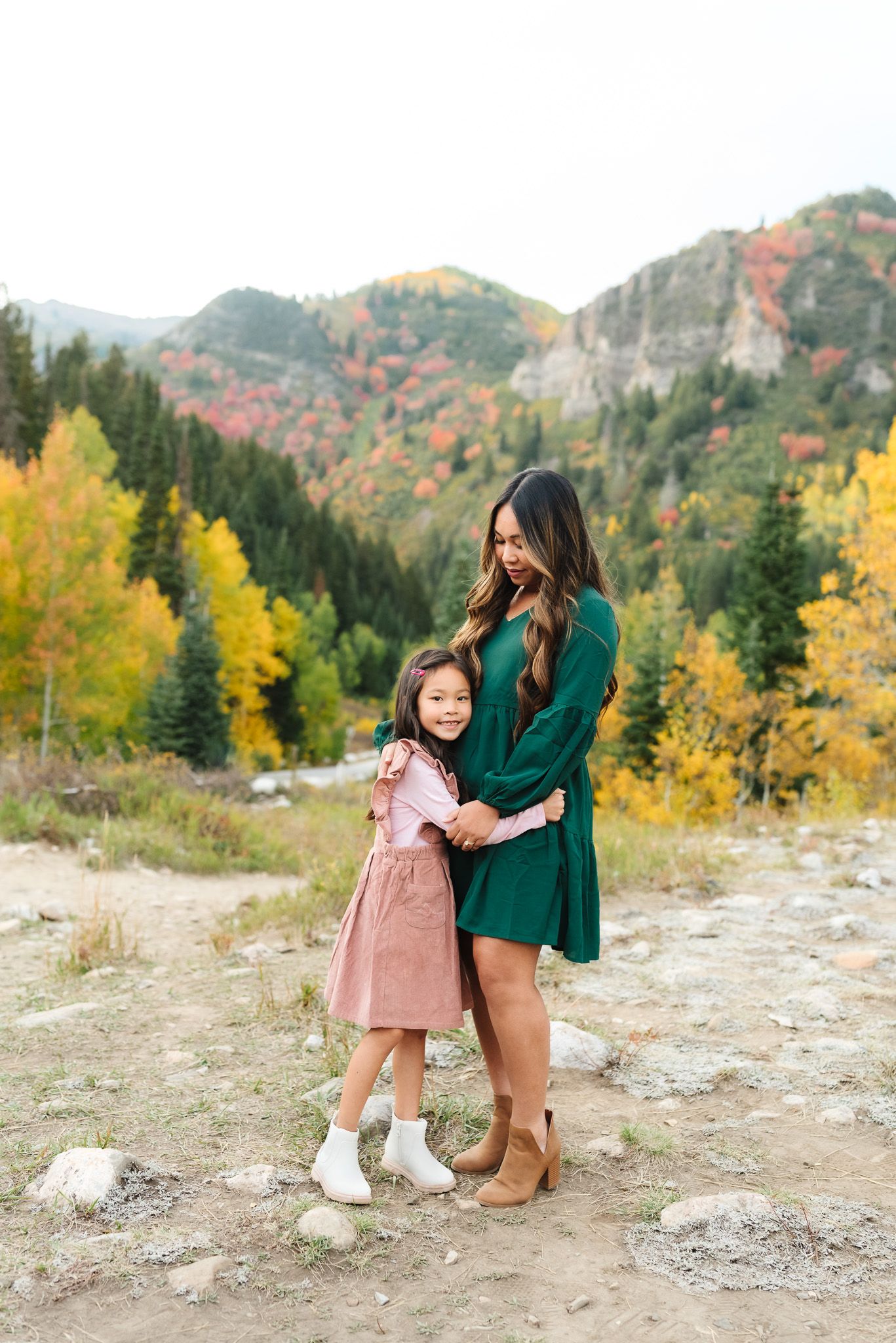 Mother and daughter walking together in a rocky mountain landscape with autumn colors.