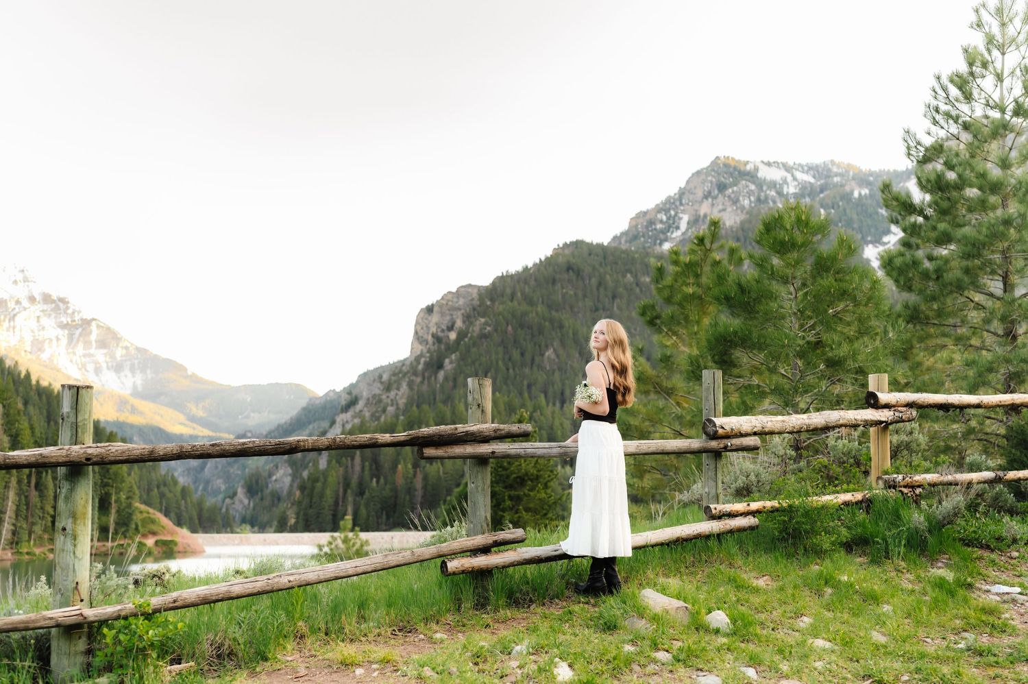 Panoramic mountain landscape photo with rustic wooden fence and natural scenery.