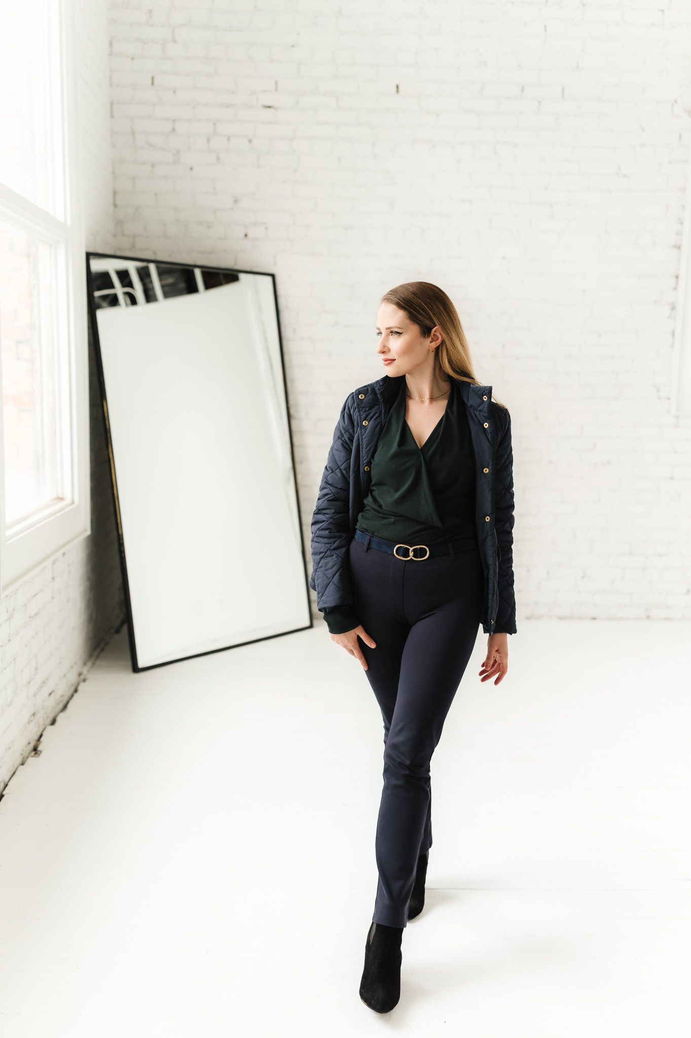 Stylish portrait in leather jacket and dark outfit against minimalist white studio backdrop.