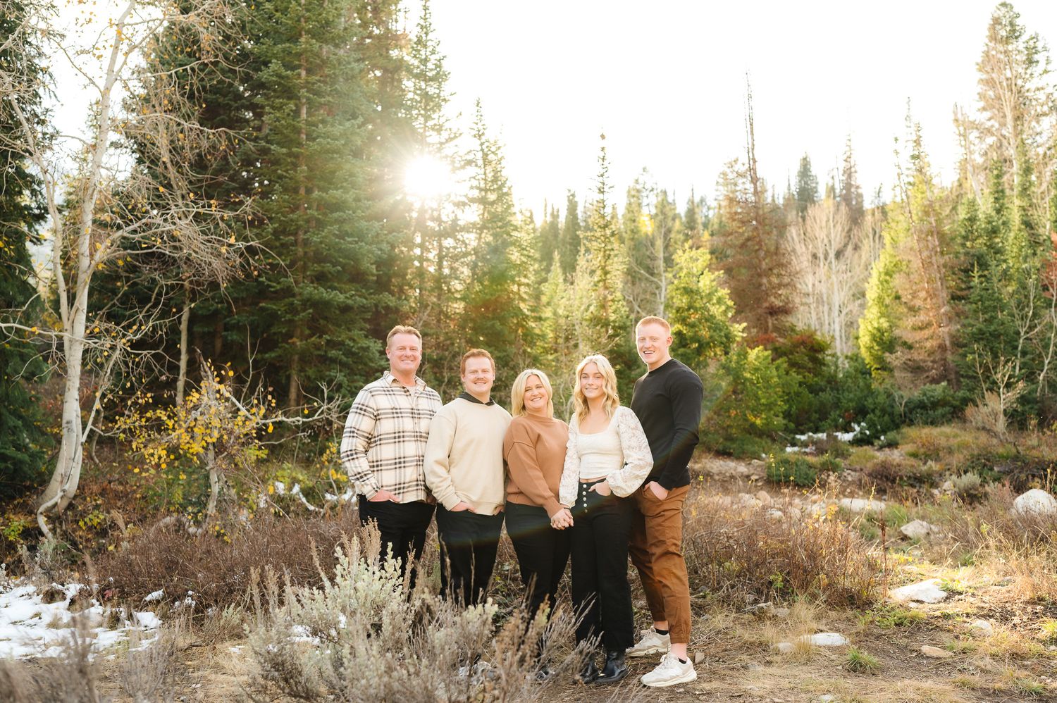 Extended family gathering outdoors with mountain scenery and evergreen trees in background.