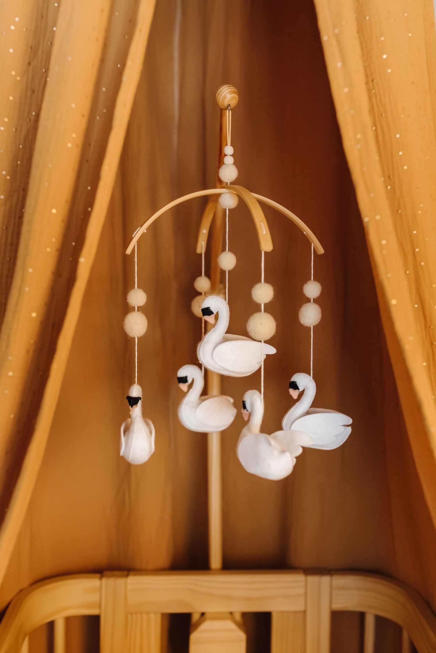 White swan mobile hanging from a golden canopy with twinkling lights.