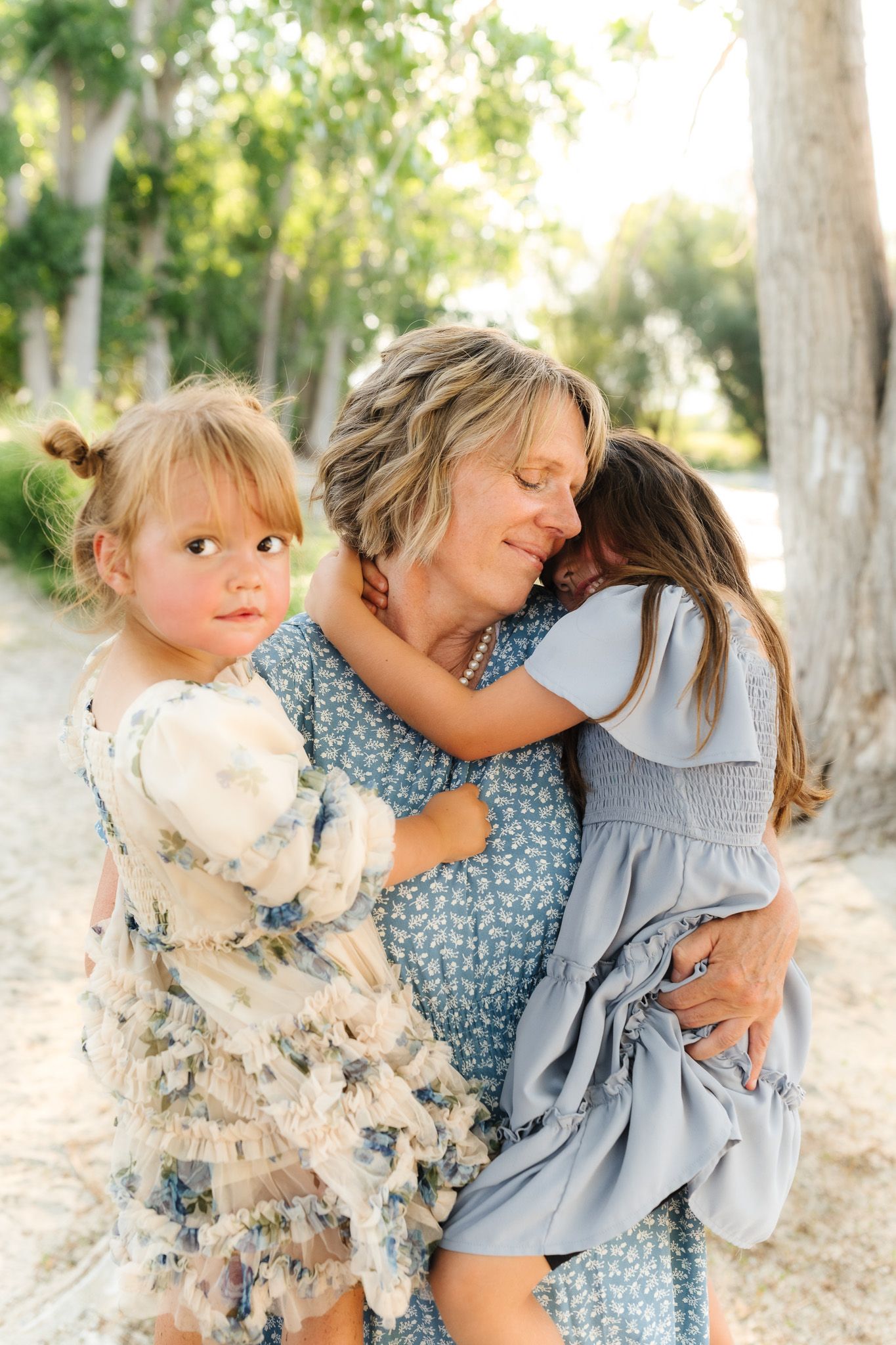 An intimate family moment shared between three generations in a sunlit outdoor setting.