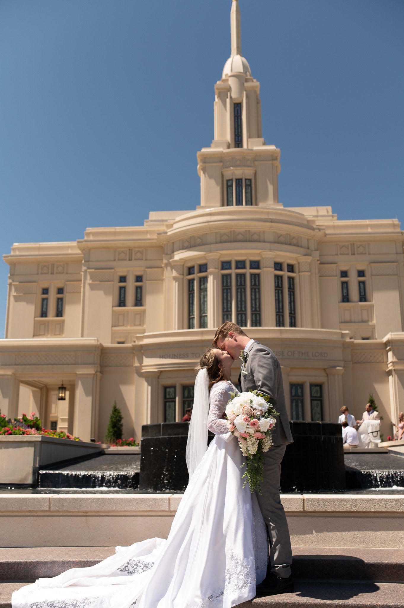 Wedding photos taken outside a grand white Mormon temple building under blue skies.