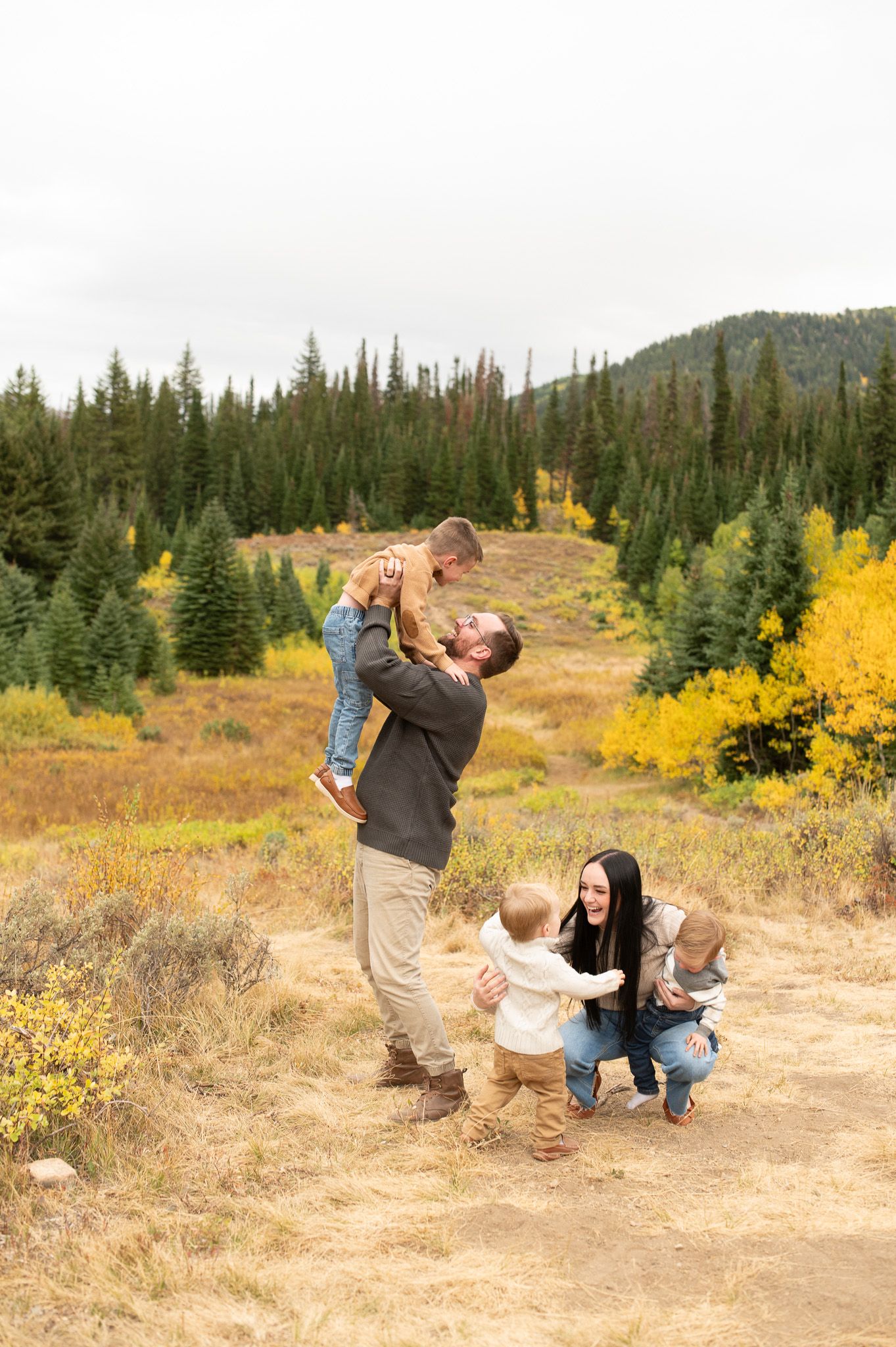Family with three young children enjoying autumn mountain landscape with colorful fall foliage.