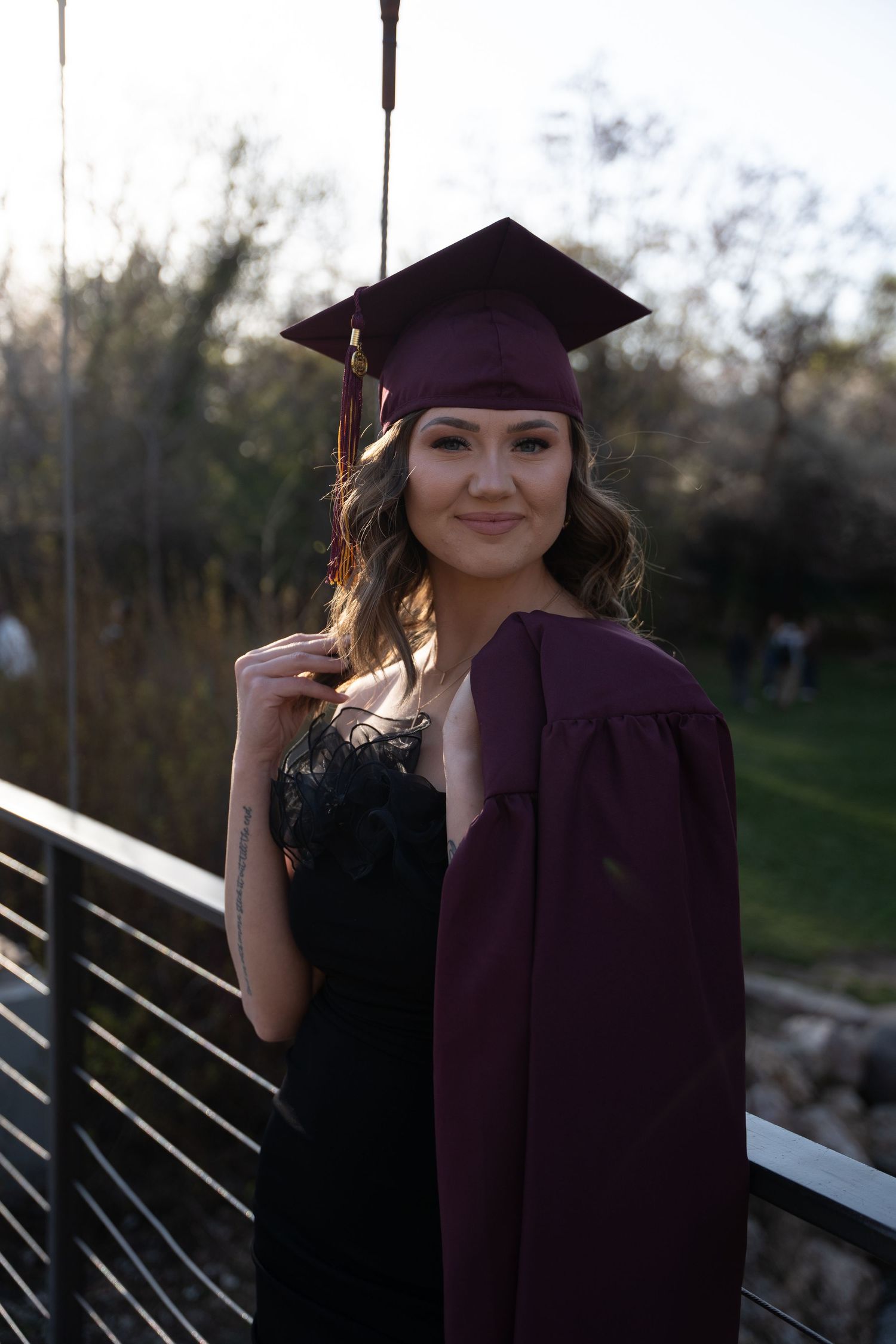 Graduation photoshoot series featuring maroon cap and gown against wooden fence.