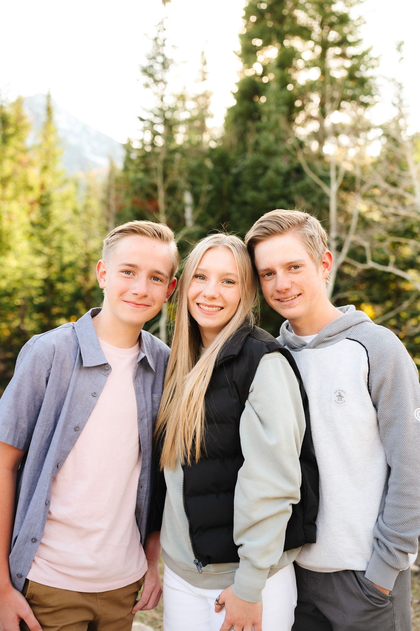 Group portrait of people in casual wear posing together in mountain setting.
