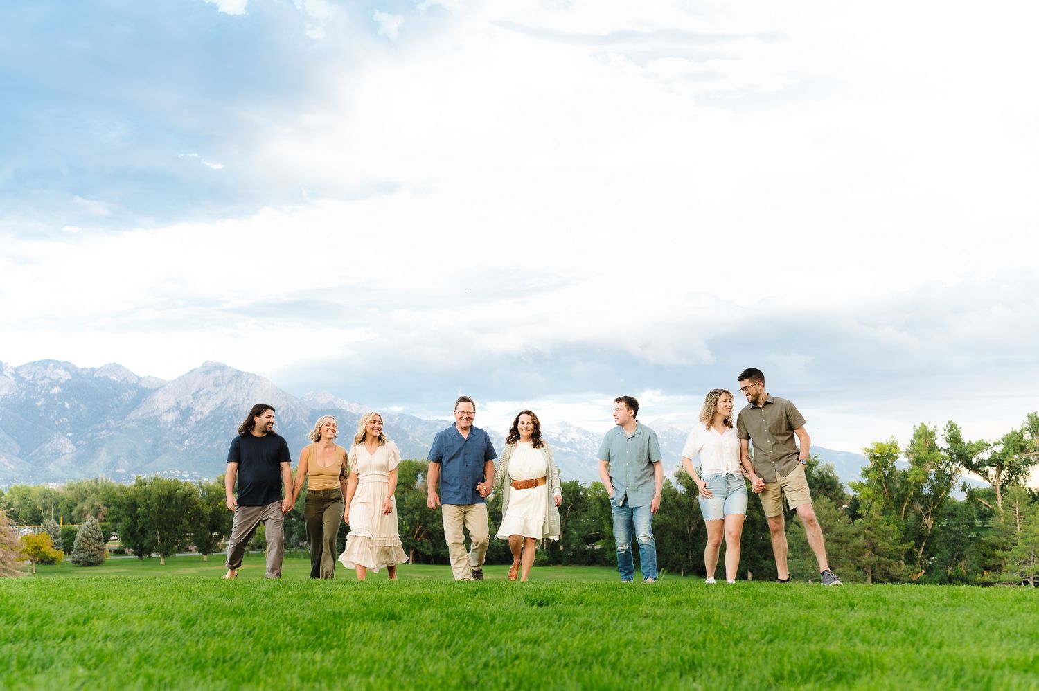 Group photo of people lined up in a grassy field under a bright blue sky.