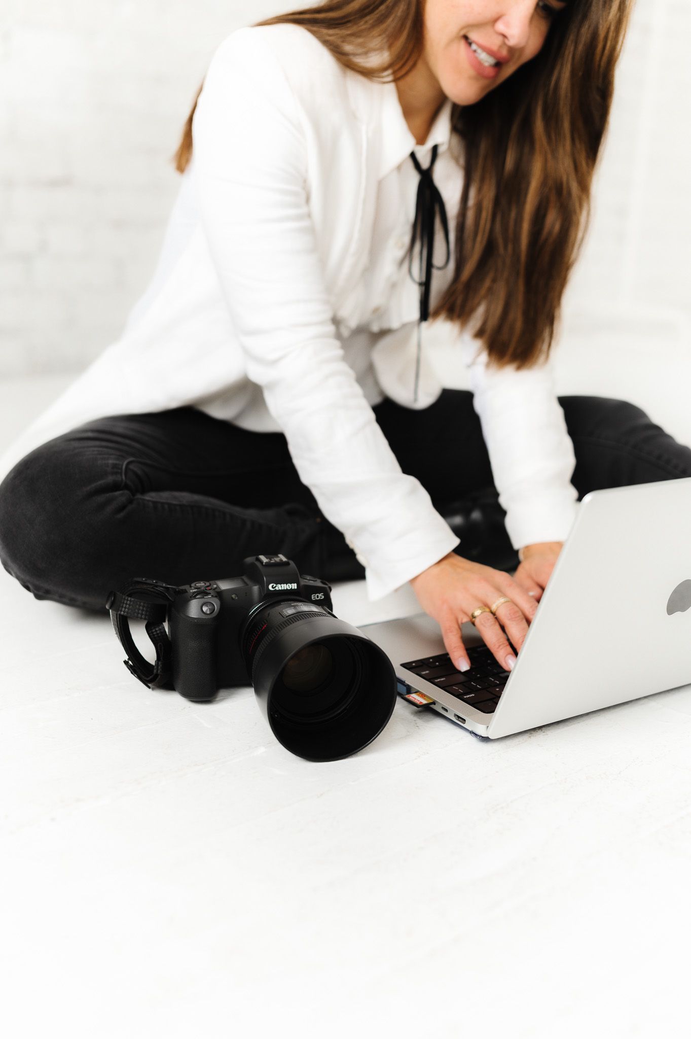 Close-up of photographer working on laptop with professional camera equipment nearby.