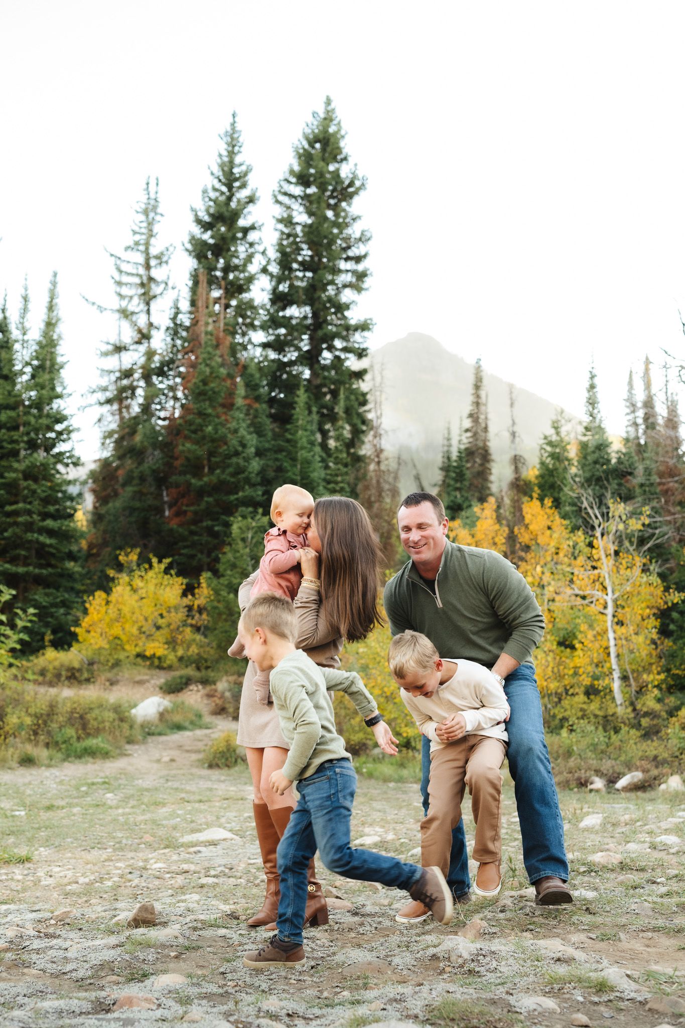 A family photoshoot showing joyful moments against a backdrop of autumn mountains.