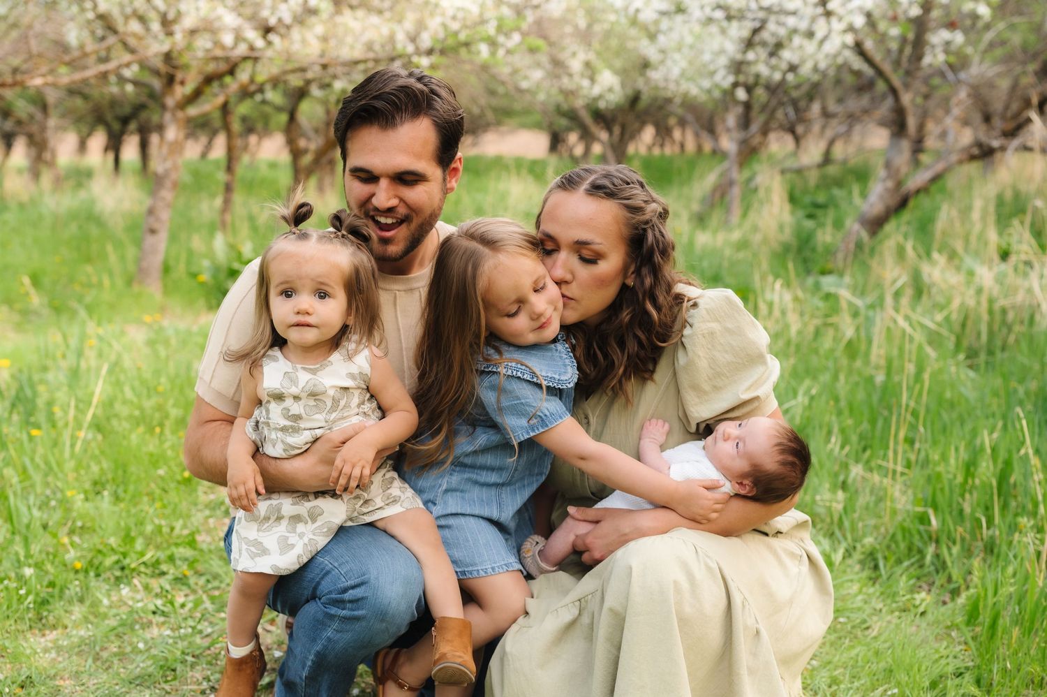 Family sitting together in a grassy meadow during golden hour outdoor photo session.