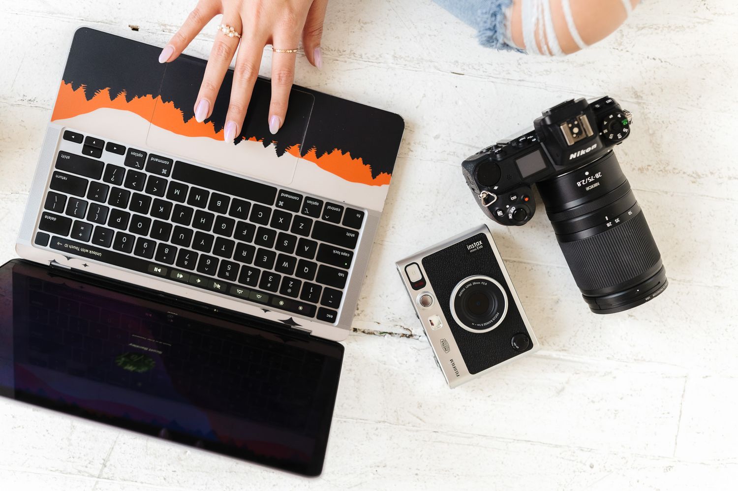 Creative workspace layout with camera equipment and keyboard on white desktop.
