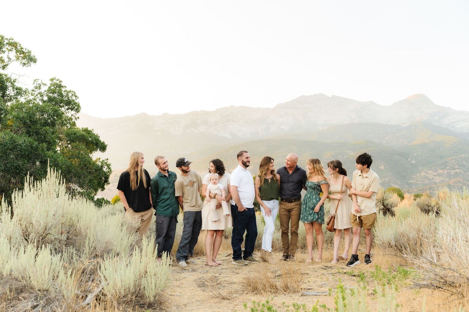 A group poses together in a scenic mountain landscape during golden hour.