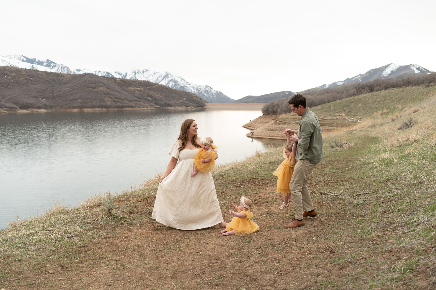 Couple's photoshoot on a hillside with dramatic mountain and lake landscape.