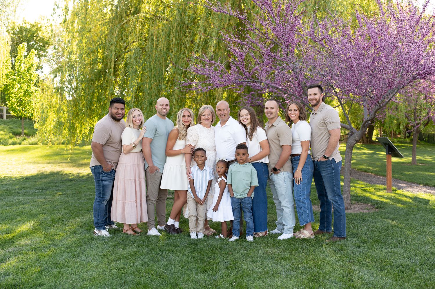 Large family gathering posed together under spring blossoms.
