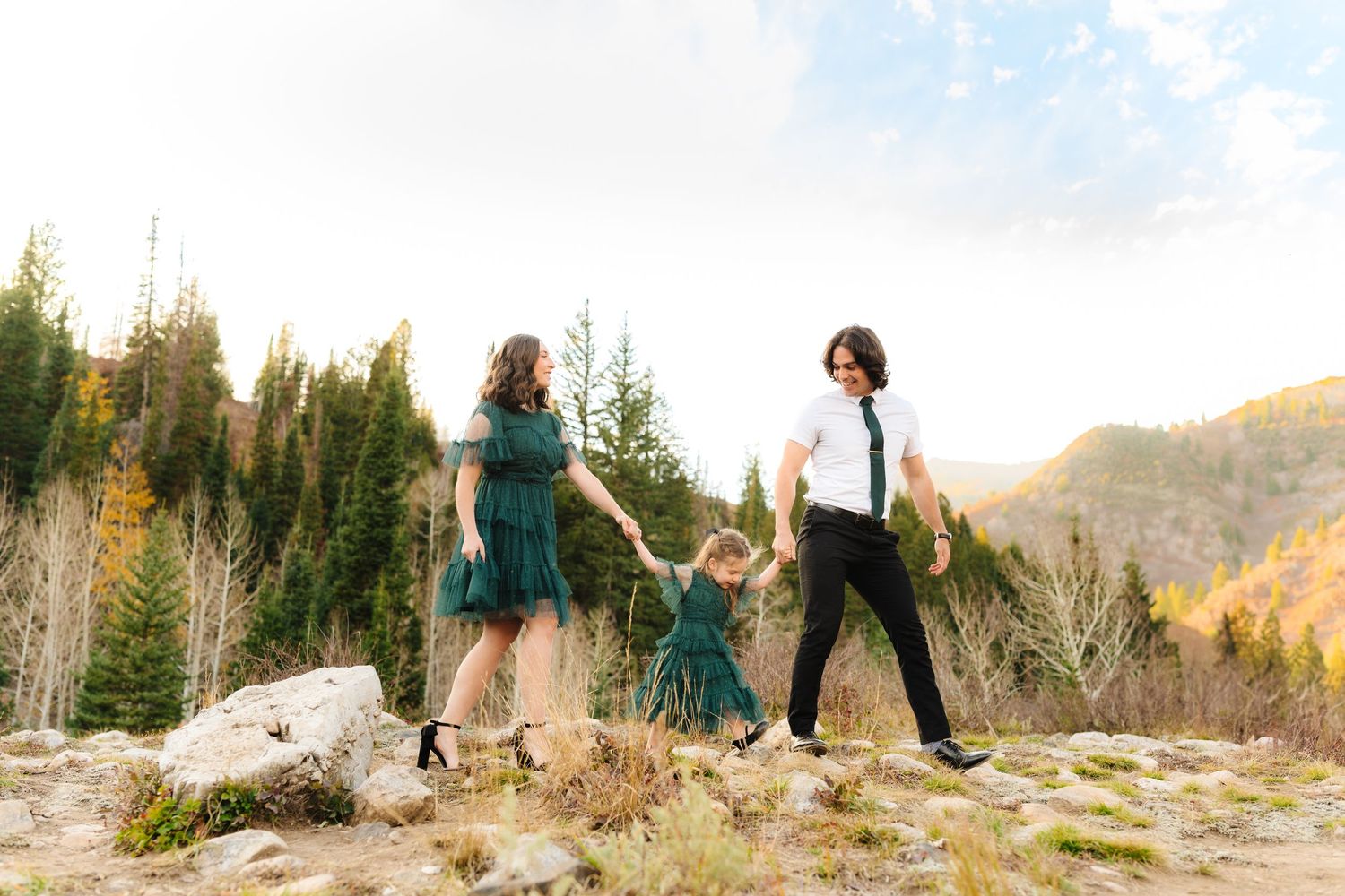 Playful family photo session in a mountain setting during sunset.