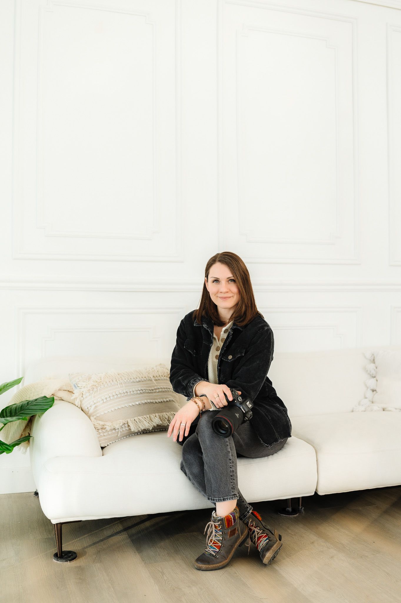 A casual portrait of a photographer sitting on a white couch in a bright room.