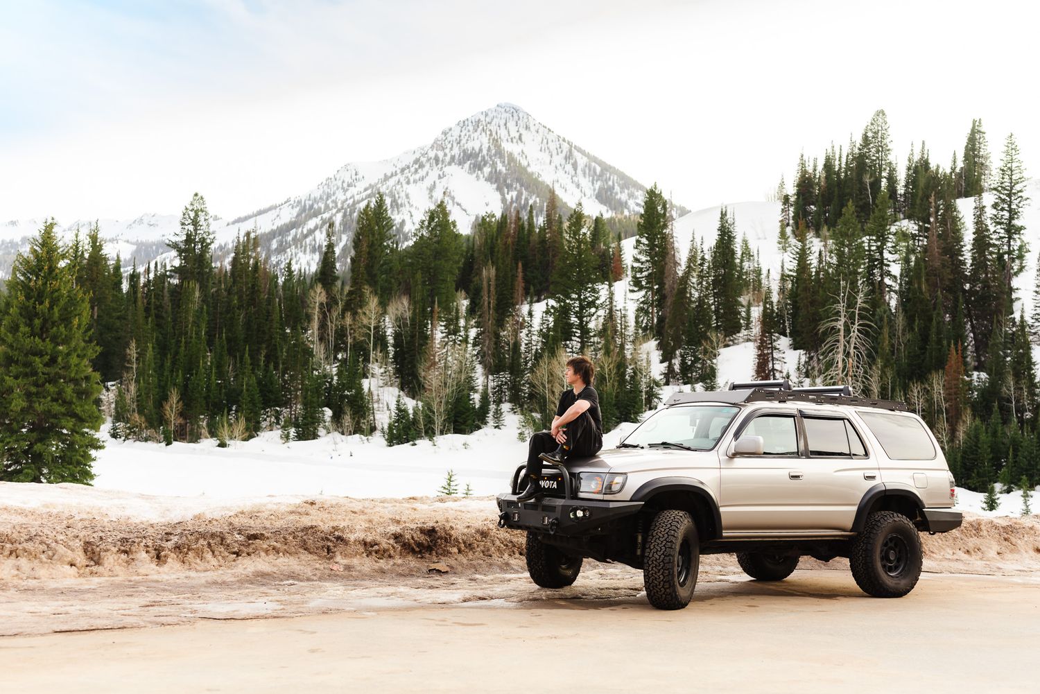 Snow-capped mountain peaks rise above evergreen forests in a scenic winter landscape.
