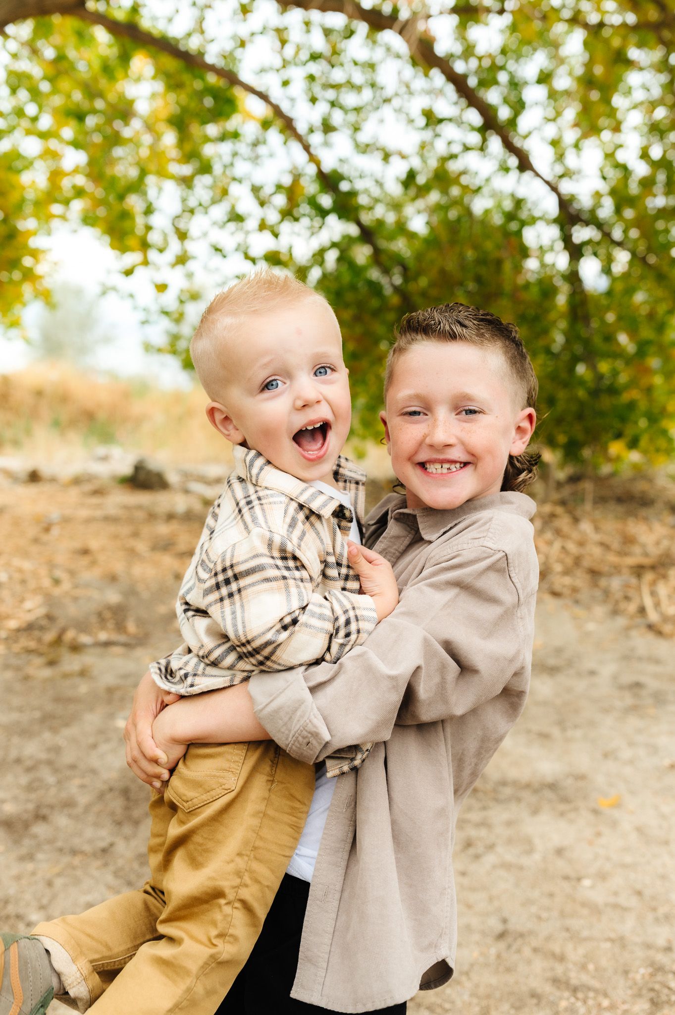 Two children playing and hugging with joyful expressions outdoors.