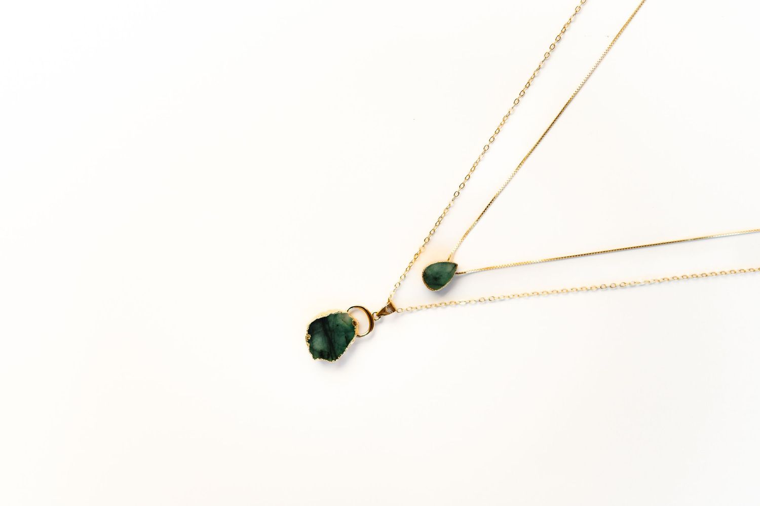 Minimalist gold chain necklaces with small pendant details on white background.