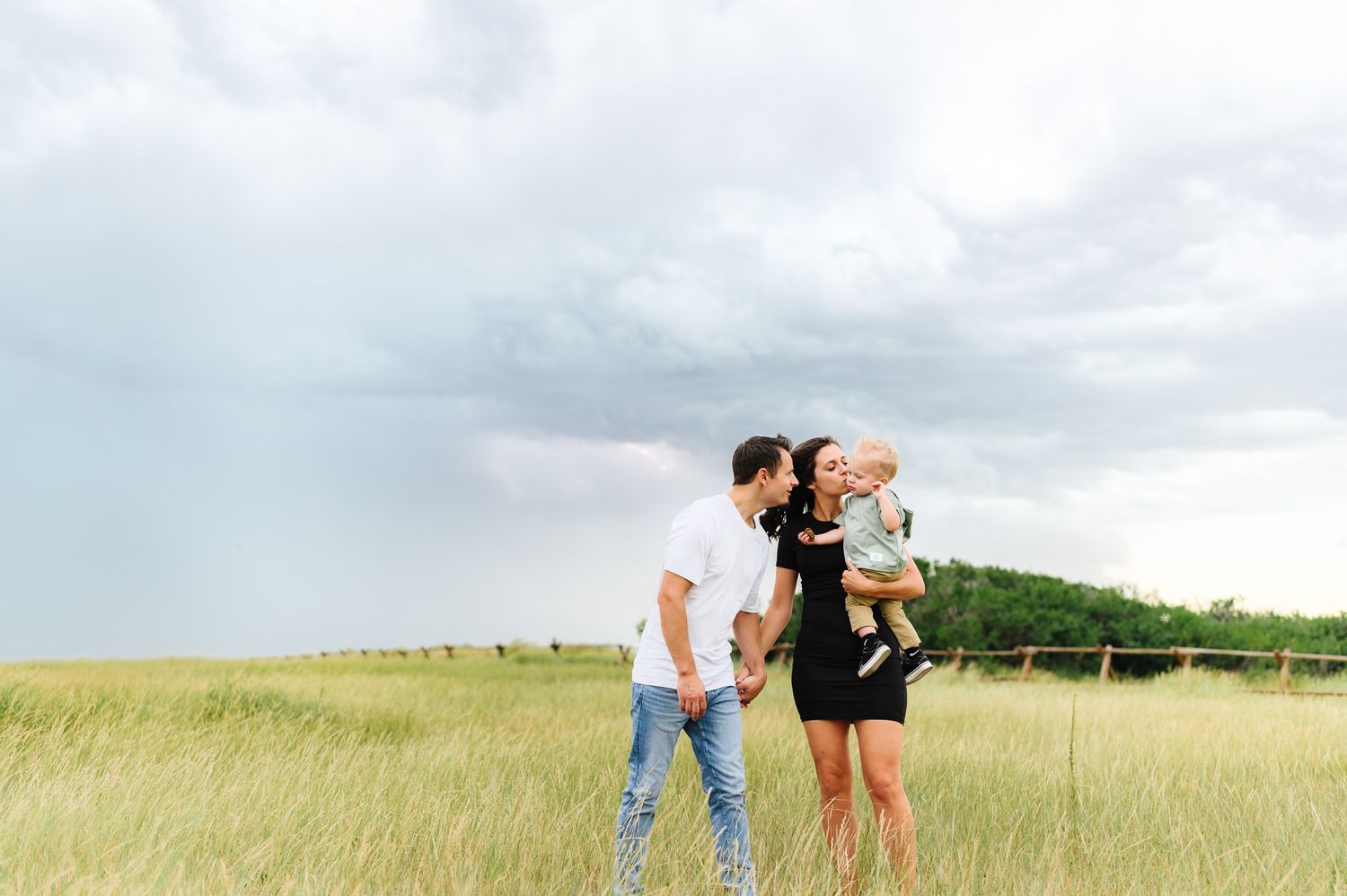 People walking through a grassy field under cloudy skies.