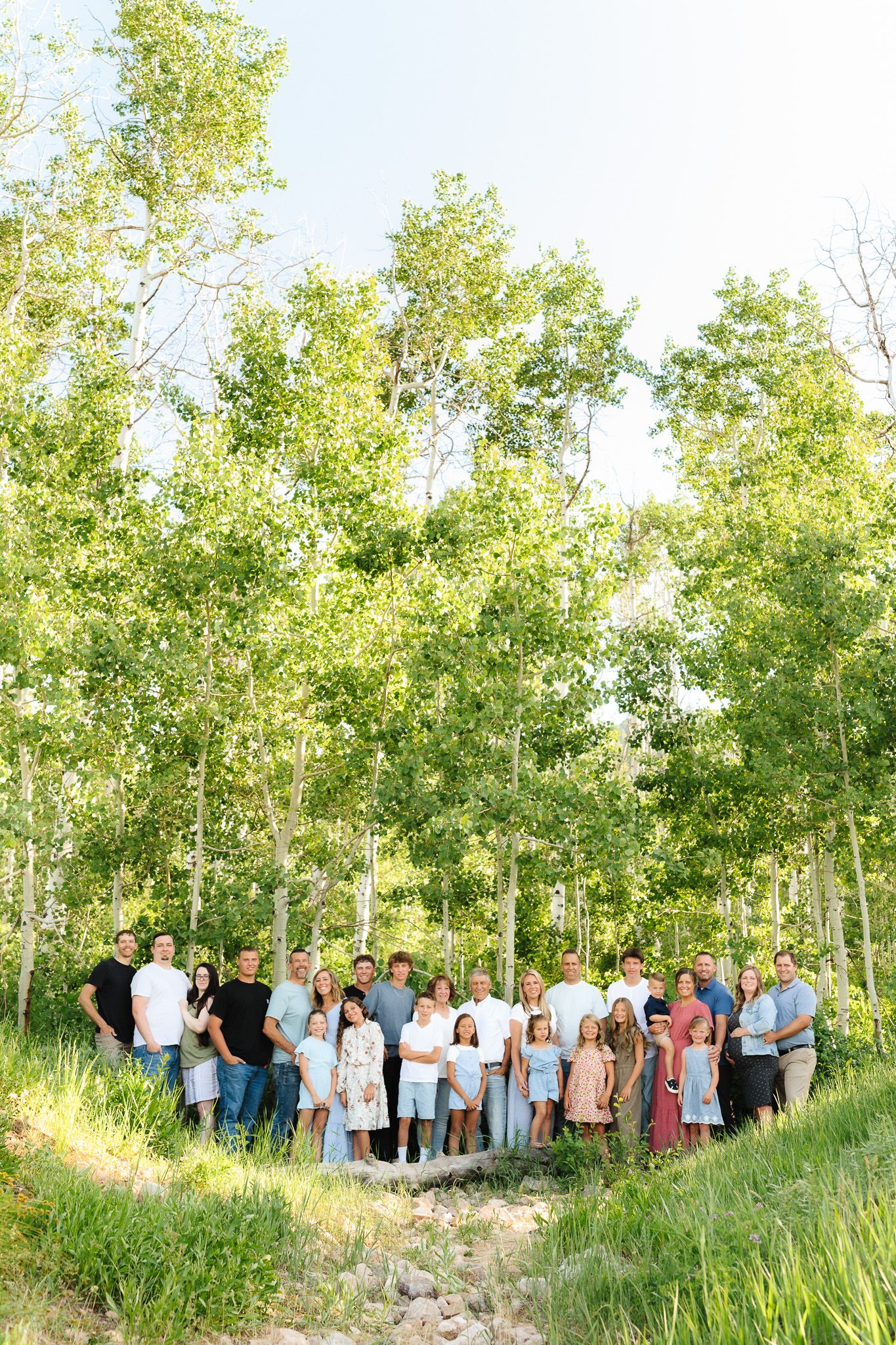 A large group stands together among aspen trees in a natural outdoor setting at Snow Basin, Utah