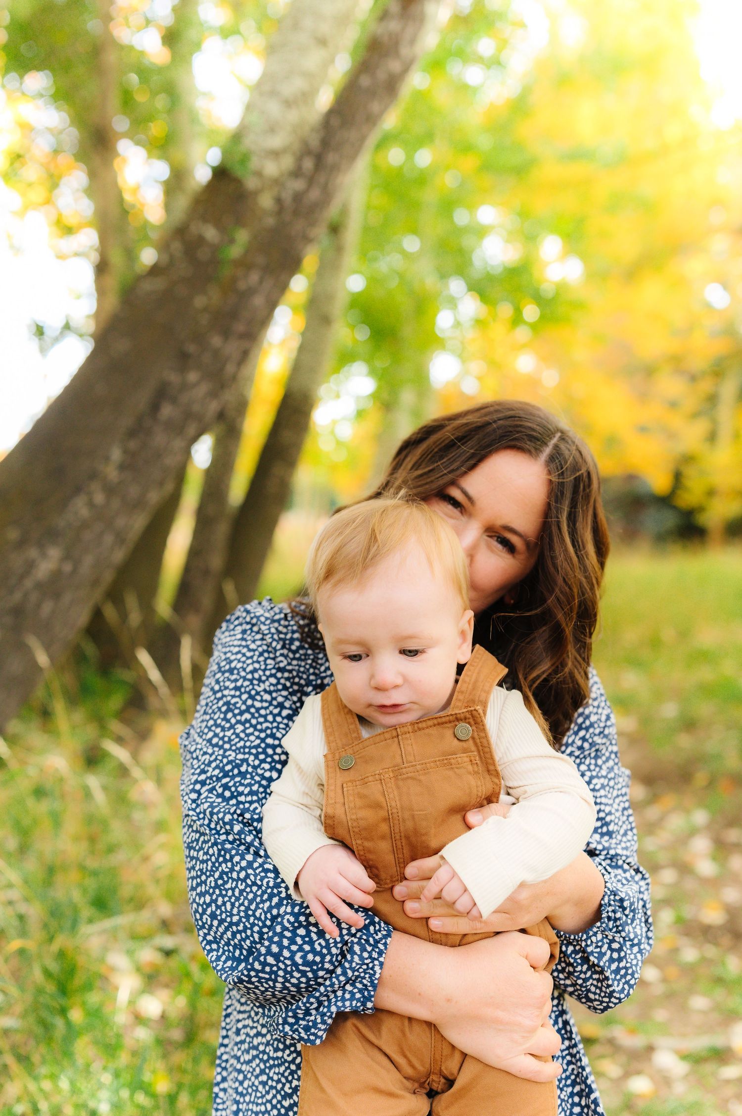 A heartwarming autumn scene showing tender moments between parent and child in brown and blue outfits.