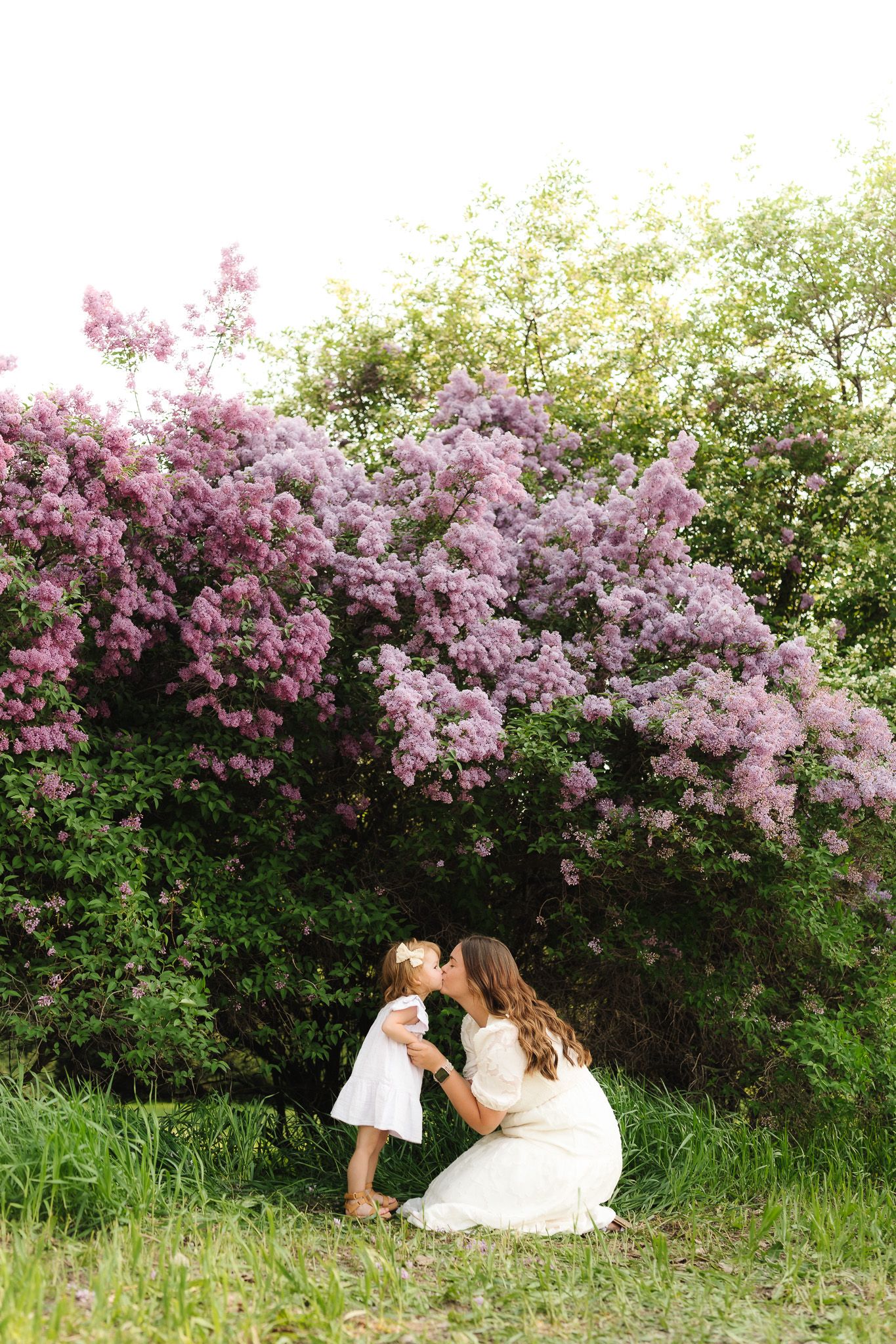 Sweet outdoor photography session among blooming lilac bushes in spring.