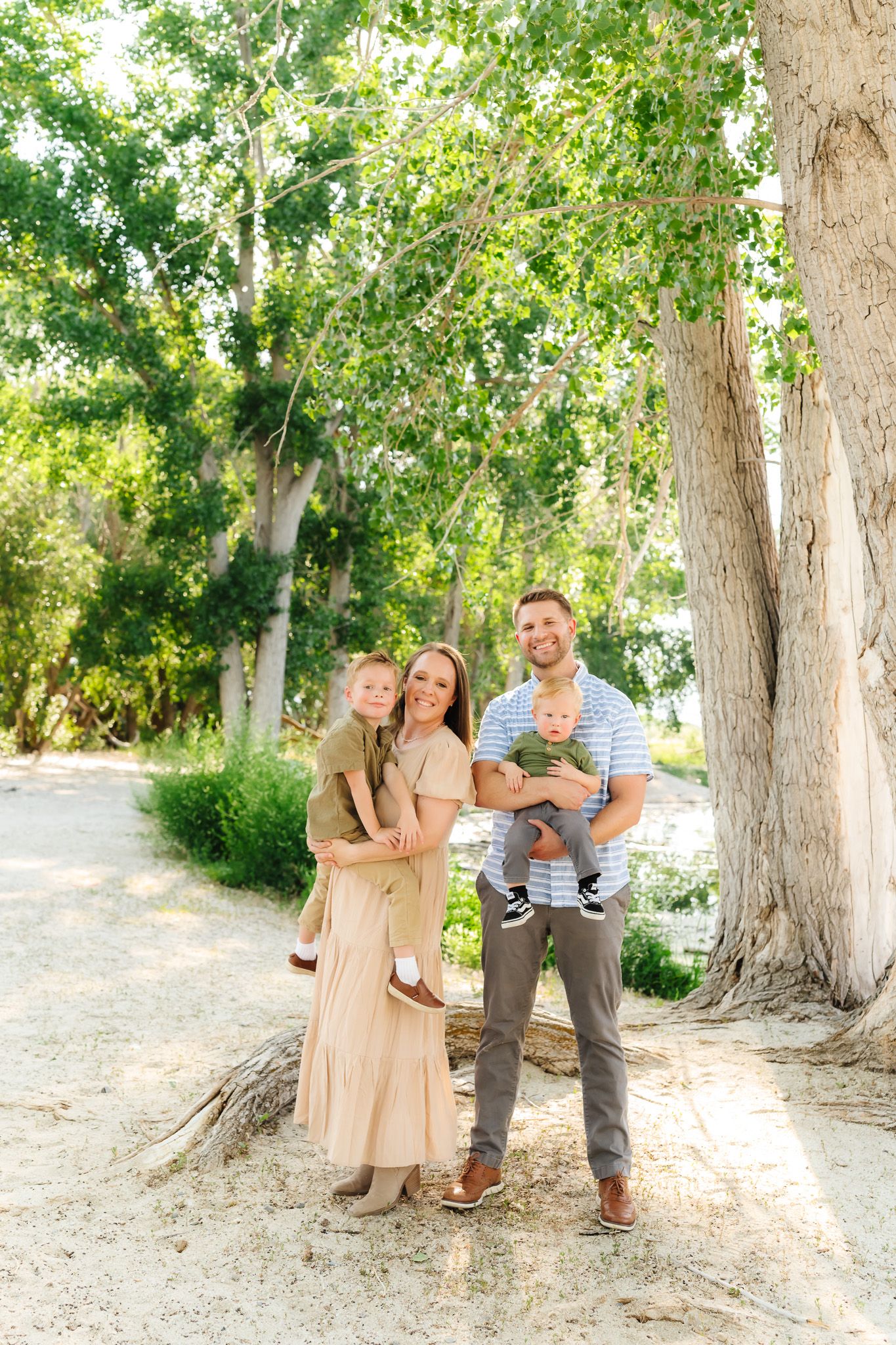 Family group poses together among tall trees in a natural outdoor setting.