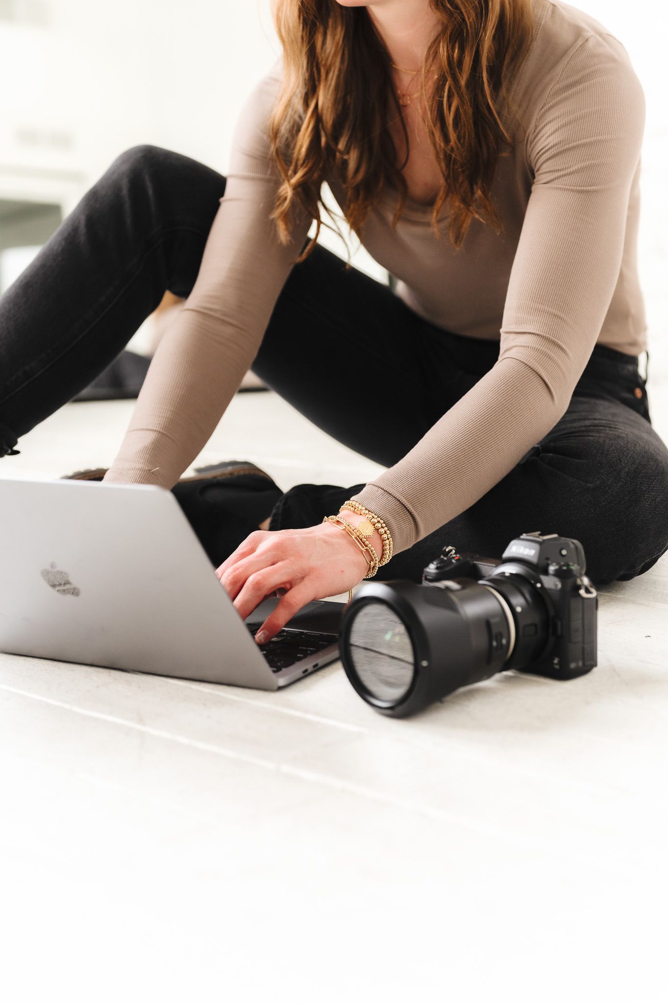 Photographer working with camera and laptop in casual studio setting.
