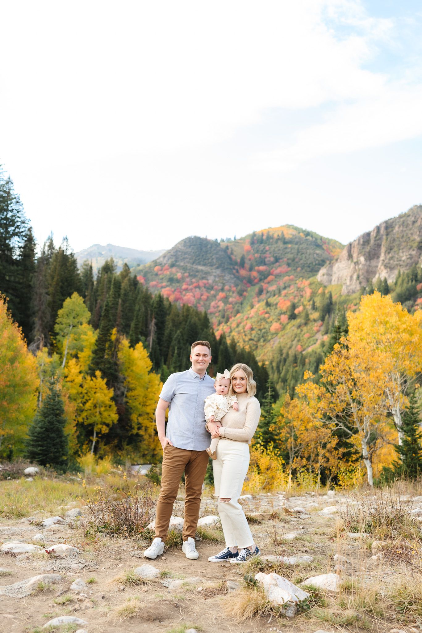 A couple poses together on a mountainside with vibrant yellow aspen trees in the background.