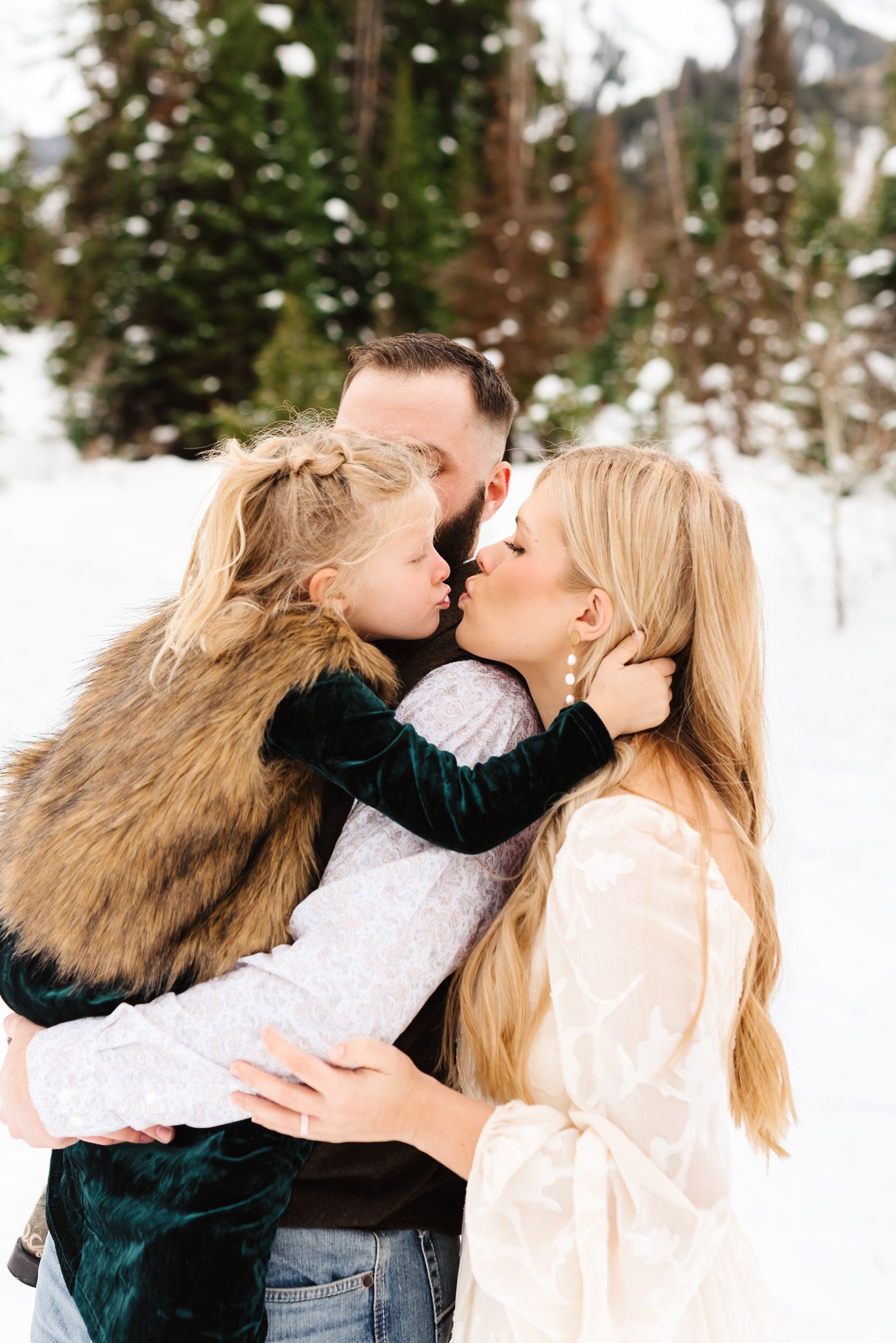Sweet family moments captured in a winter wonderland setting with snow-covered trees.