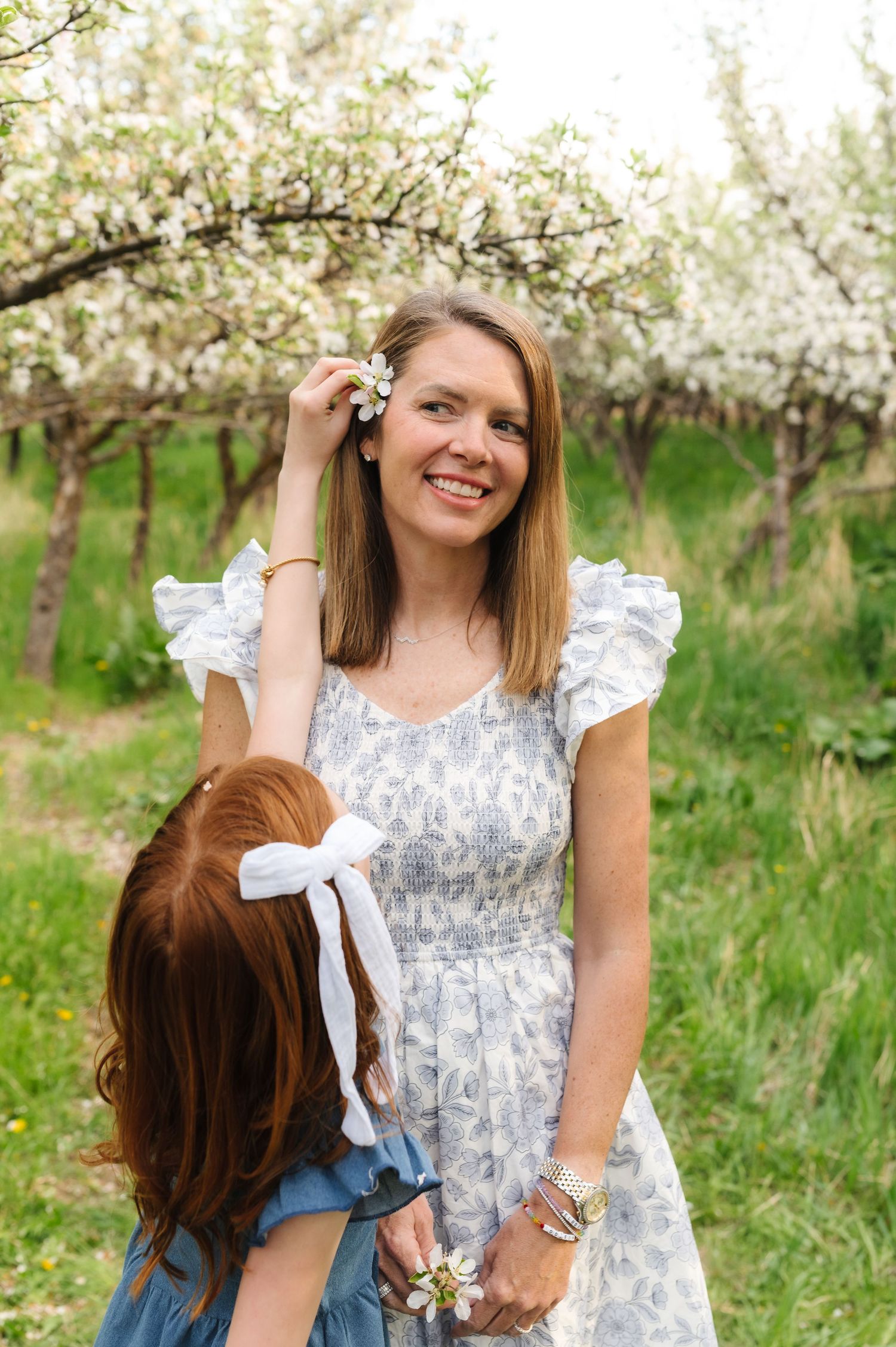 A sweet springtime portrait session in a blooming orchard with light floral dresses and joyful expressions.