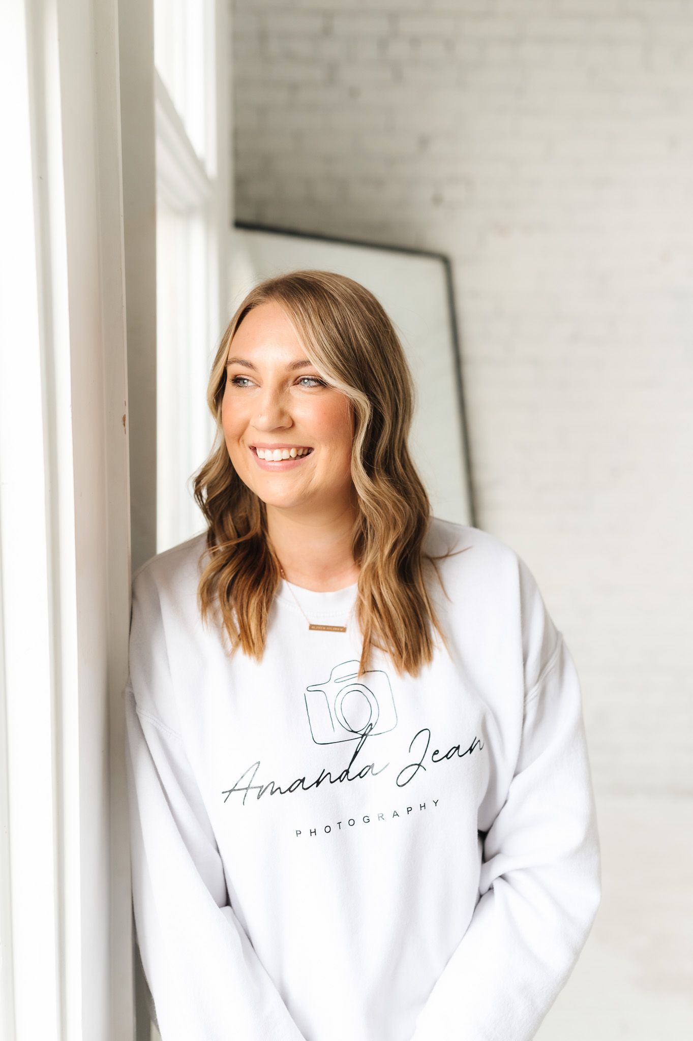 Professional photography branding session in white sweatshirt against studio backdrop.