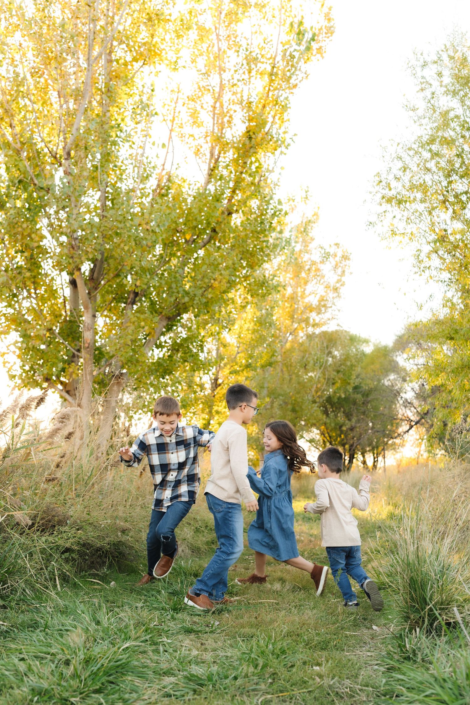 A group walks together along a grassy path surrounded by golden autumn trees on a sunny afternoon.