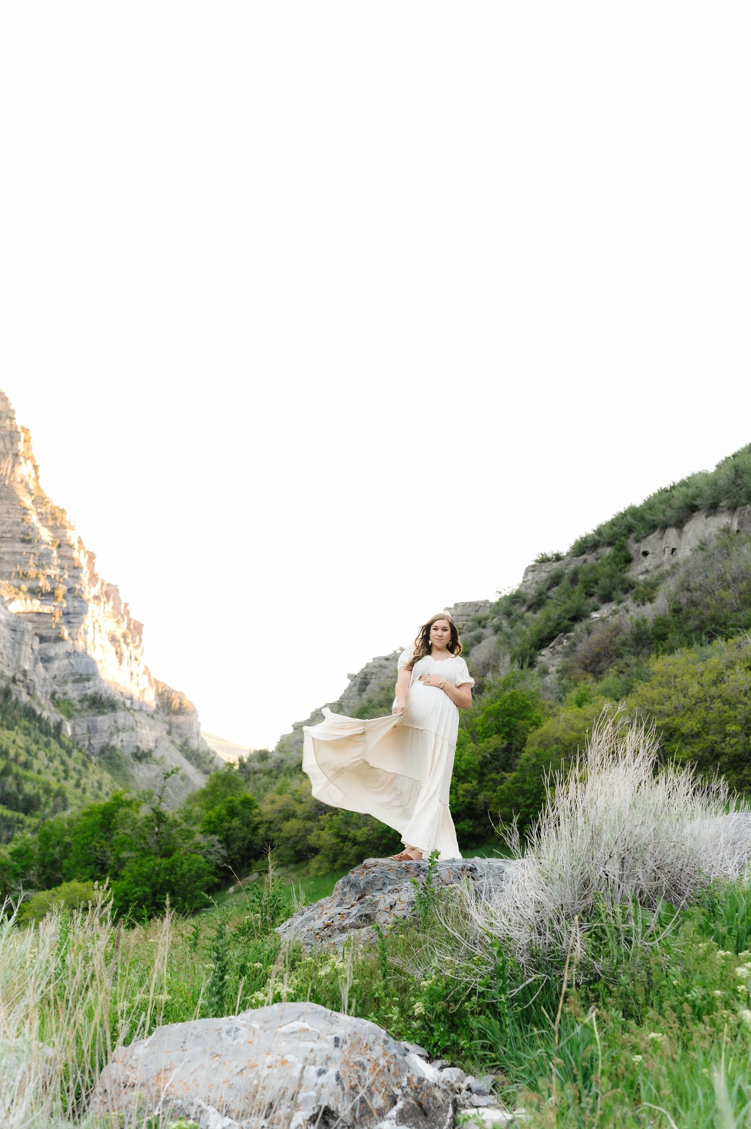 Ethereal white dress flowing in the wind against dramatic mountain cliffs and sage brush.