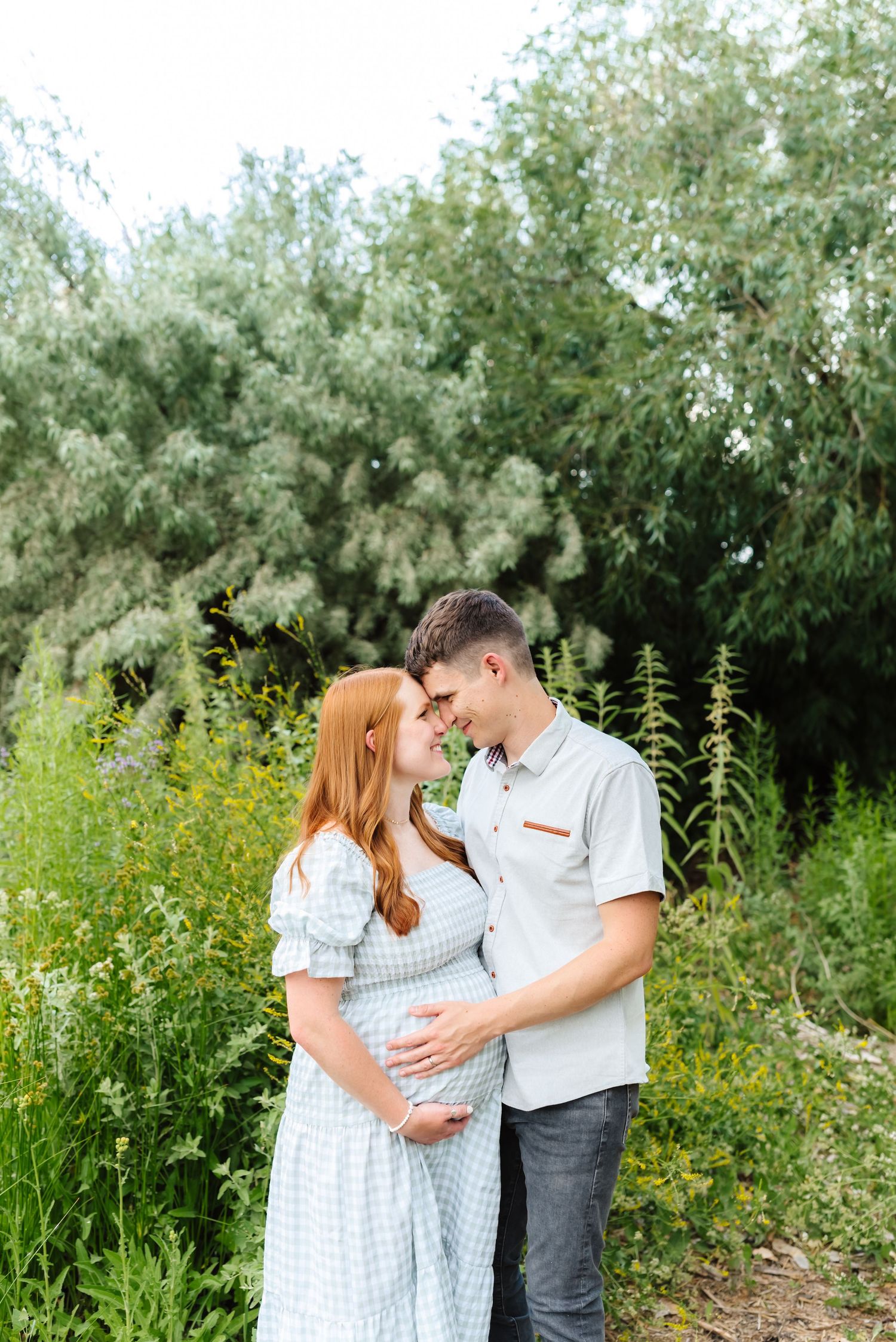 Family portrait in natural setting with wildflowers and trees in background.