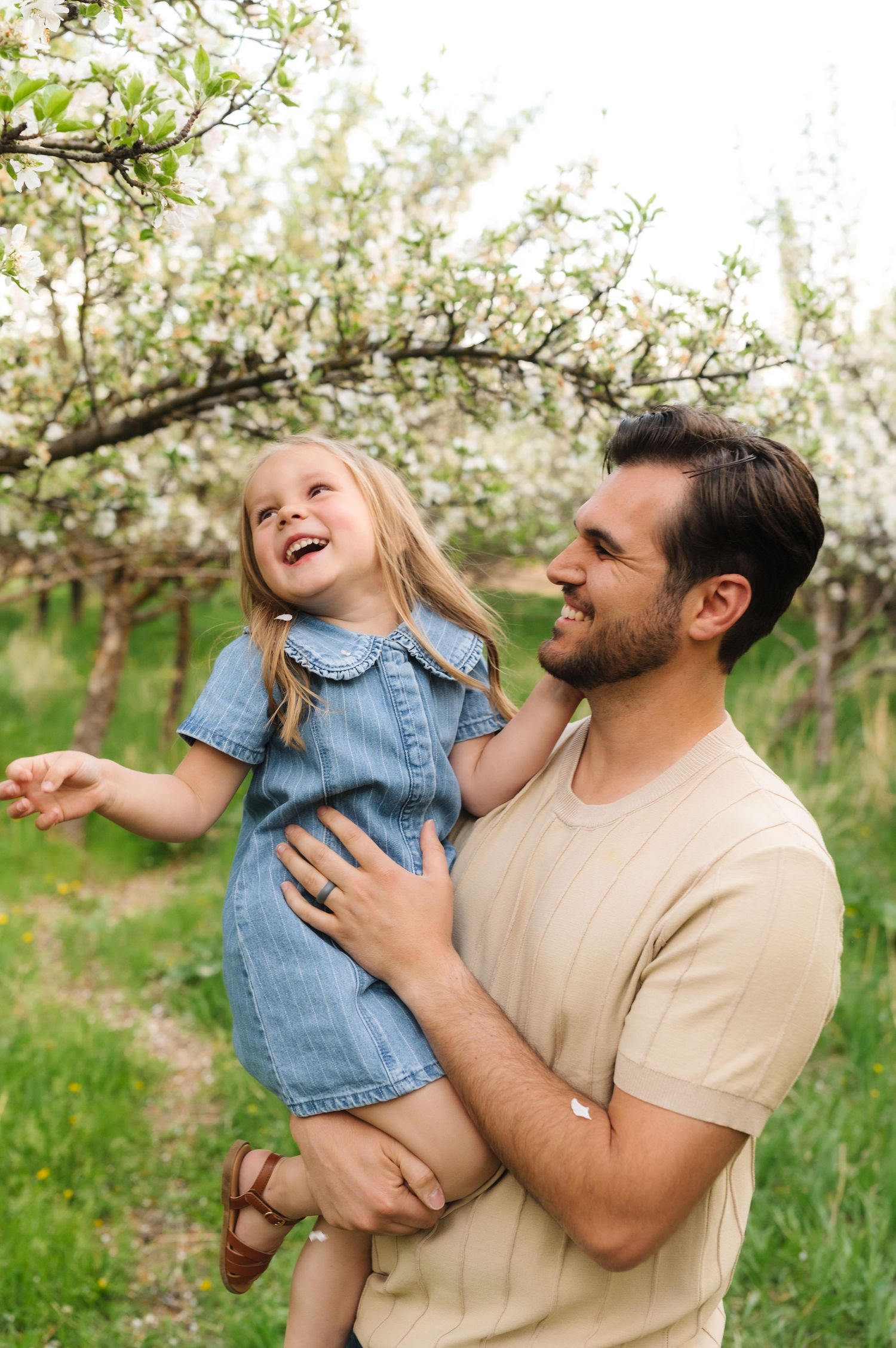 A joyful moment shared between two people in a blooming apple orchard on a bright spring day.