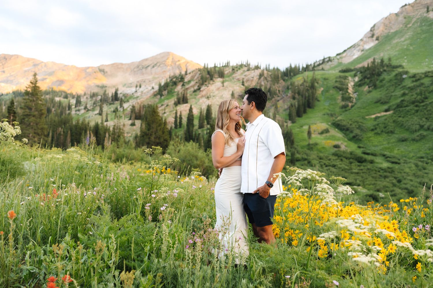 Bride and groom share tender moments against majestic mountain peaks and summer wildflowers.