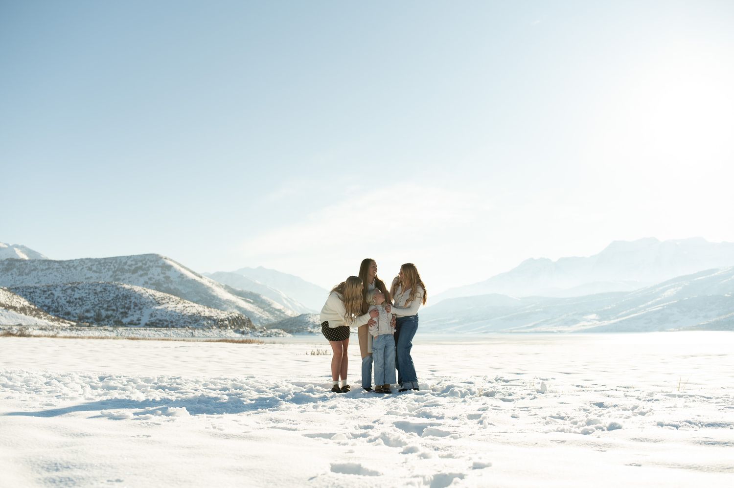 Three people standing together on a snowy landscape with mountain views on a clear winter day.