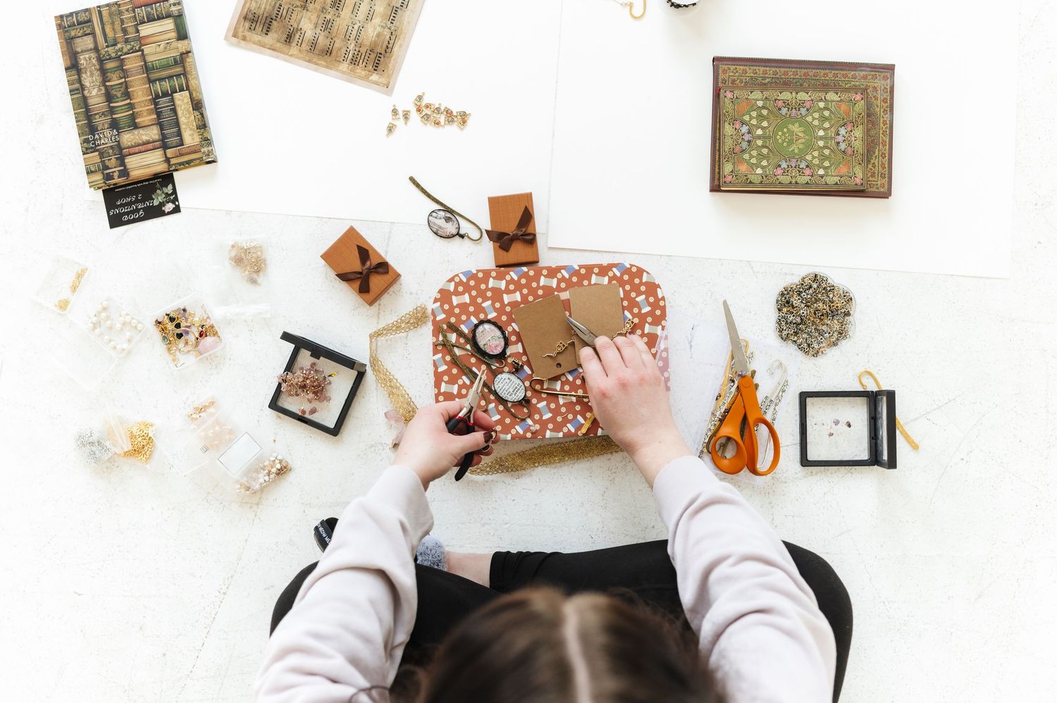 Flatlay of jewelry making supplies and tools scattered on a white workspace.