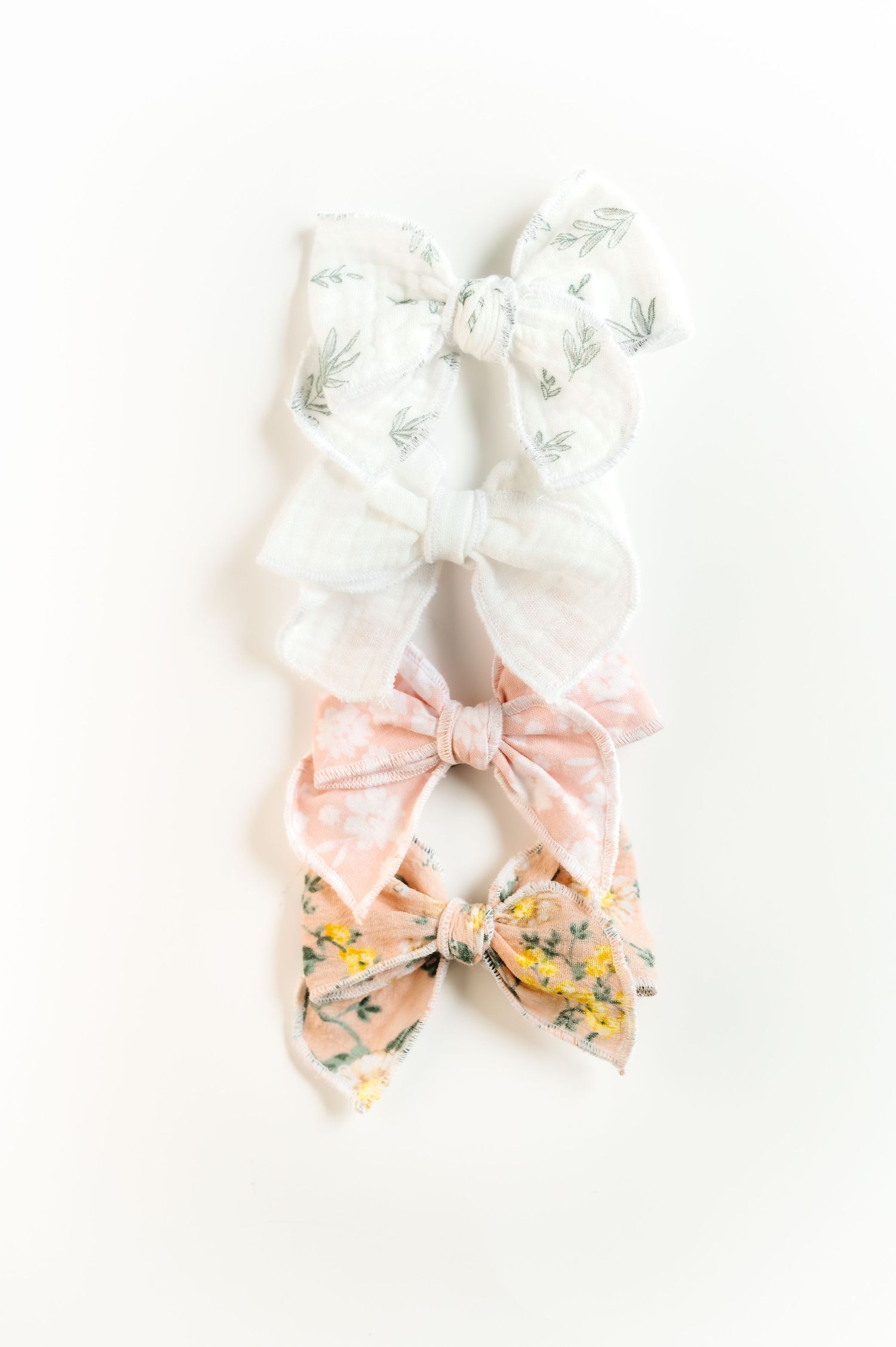 Collection of white and peach floral print fabric hair bows displayed together.