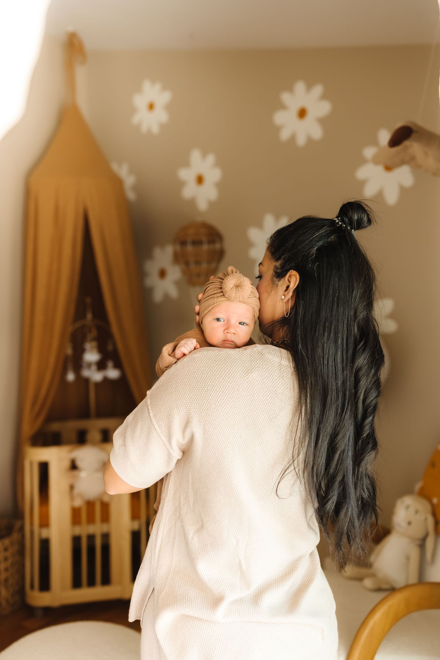 Nursery room decorated with gold canopy, white floral decals, and wooden crib.