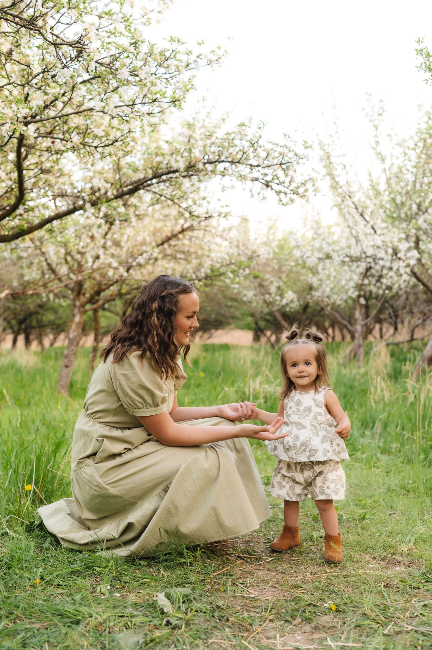 A tender spring moment in a blooming orchard with flowering trees and lush green grass.