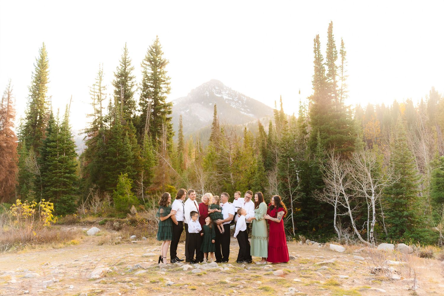 A group portrait taken in a snowy mountain landscape with evergreen trees at sunset.