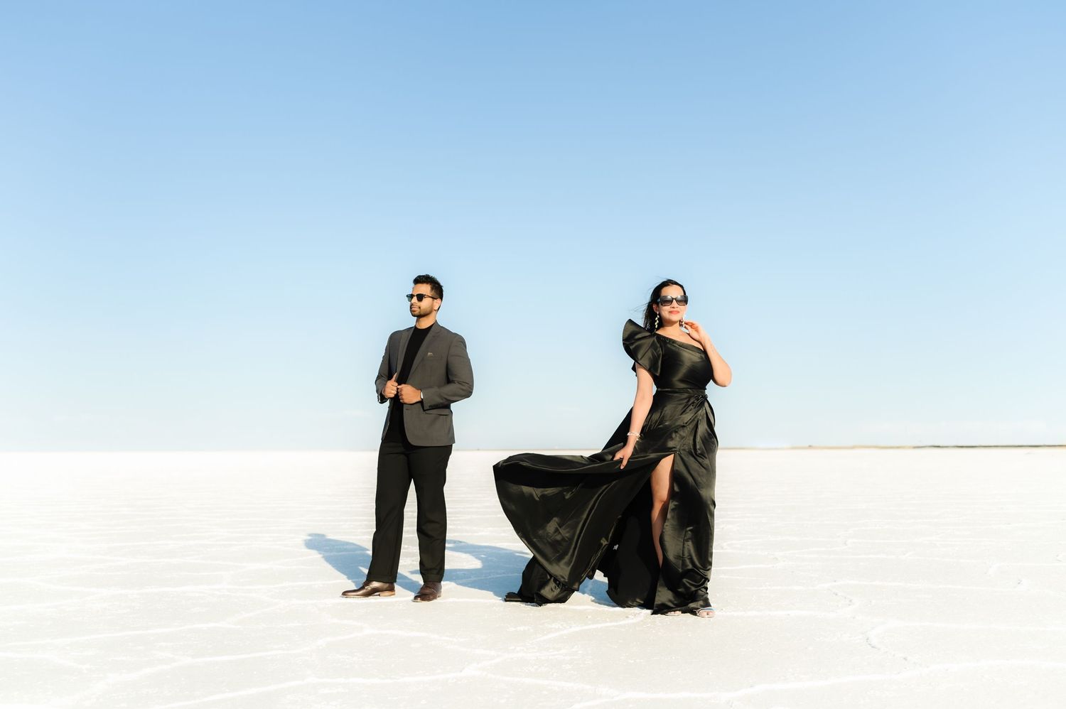 People posing on stark white salt flats against bright blue sky.