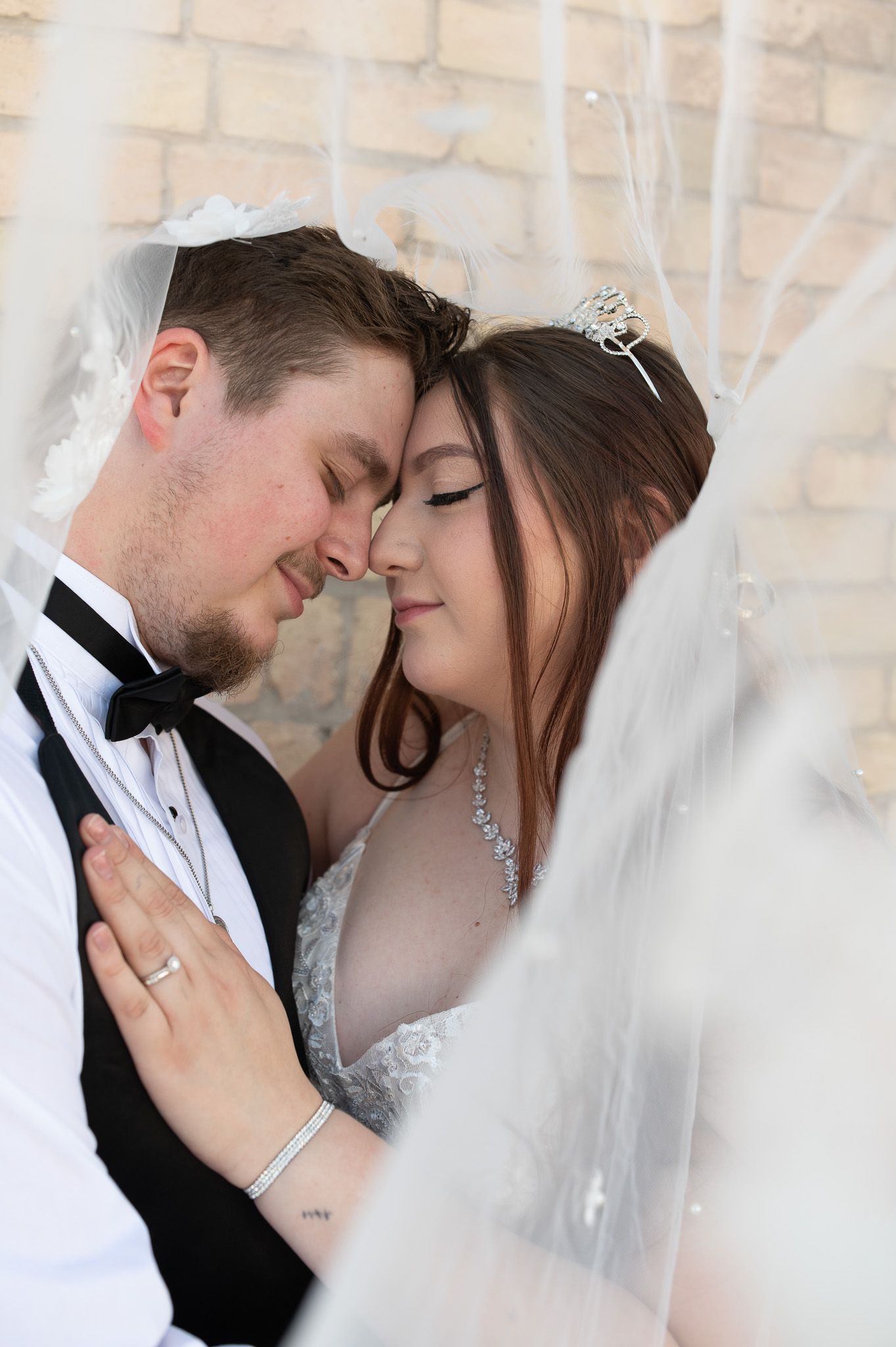 Romantic wedding portrait of a couple sharing an intimate moment under a delicate white veil.